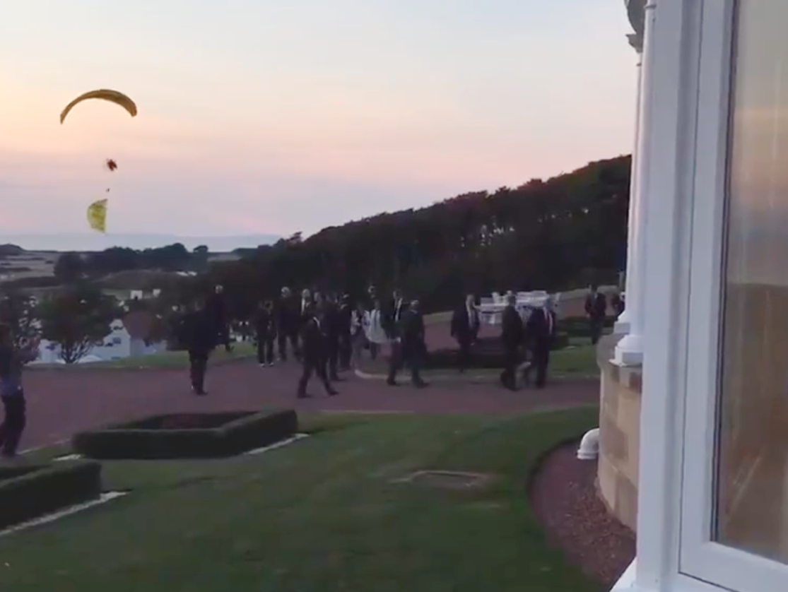 Donald Trump, centre right, rushes into Turnberry hotel as microlight approaches from coast