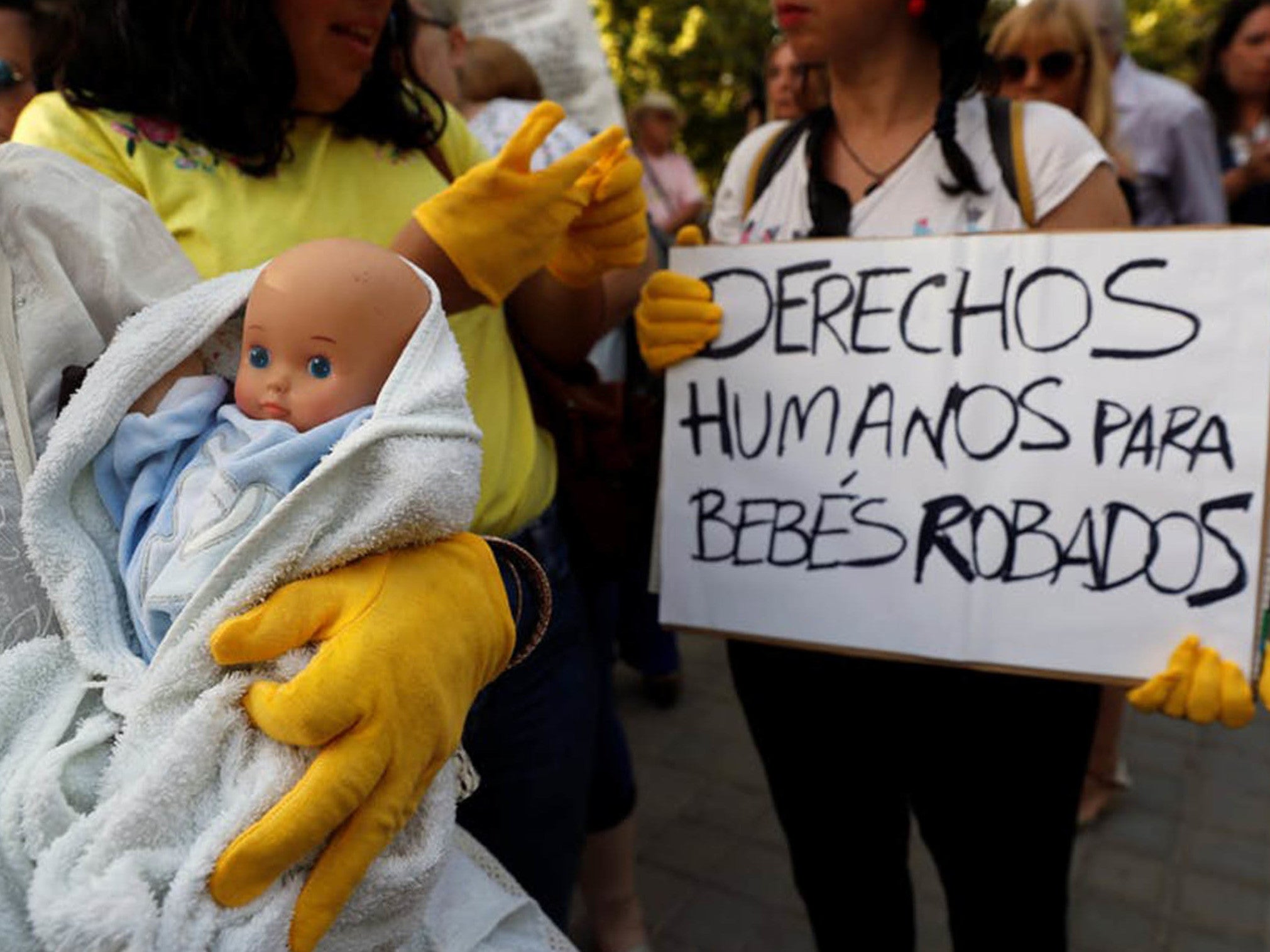 Protesters hold signs demanding "human rights" for victims of the scandal