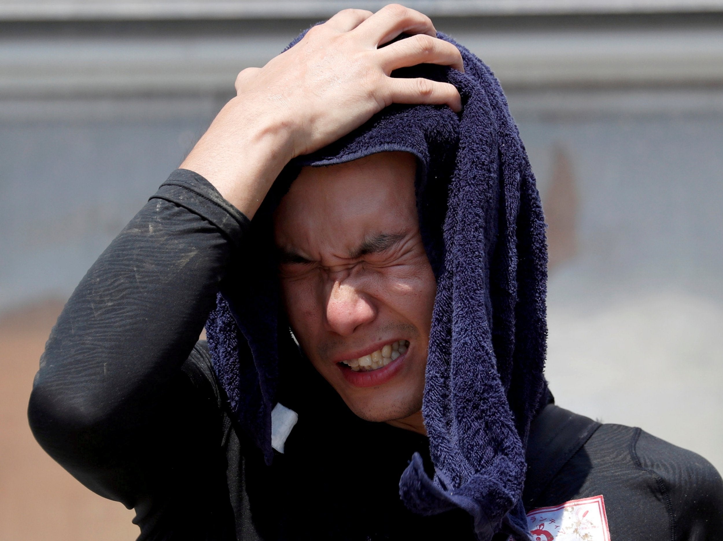 A volunteer, for recovery work, wipes his sweat as he takes a break in a heat wave at a flood affected area in Kurashiki, Okayama Prefecture