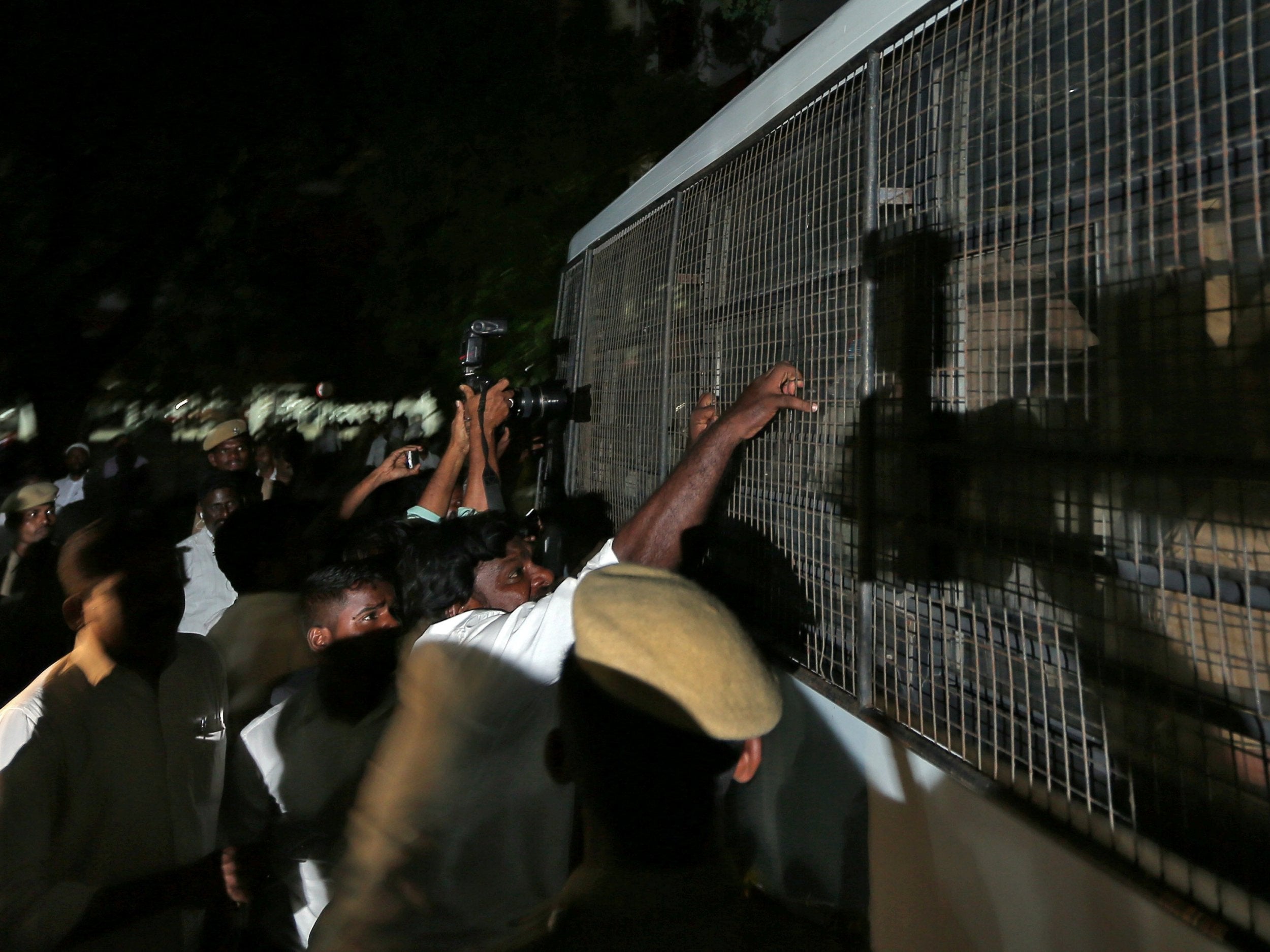 A lawyer attempts to pull the fenced window of a police vehicle carrying men (unseen) accused of raping a 12-year girl inside the high court premises in Chennai