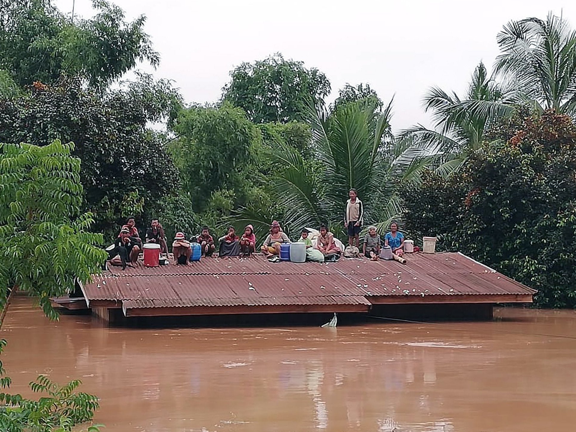 Lao villagers stranded on a roof of a house after they evacuated floodwaters