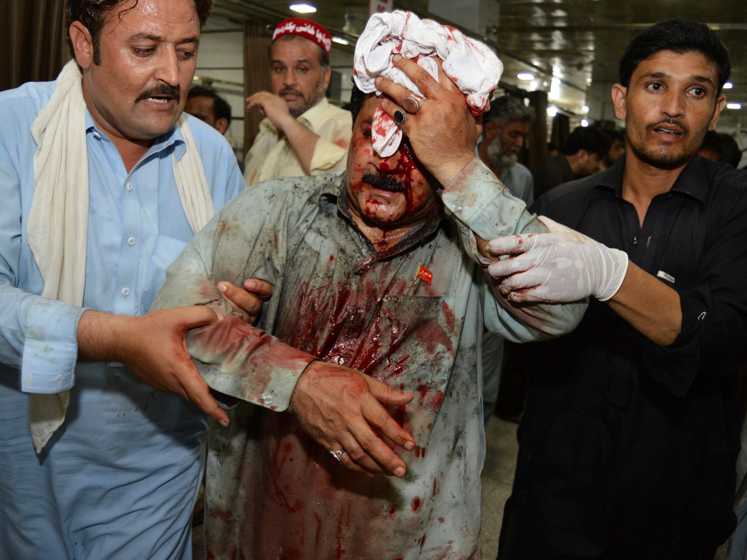 Pakistani volunteers rush an injured person to a hospital following a suicide attack on an election rally in Peshawar on 10 July