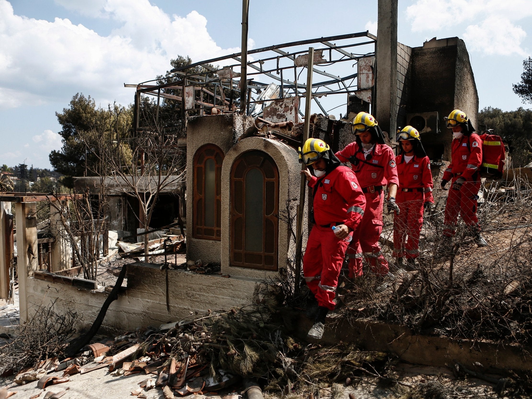 Members of the Greek Red Cross search for missing people at a burned house, following a deadly forest fire in Mati