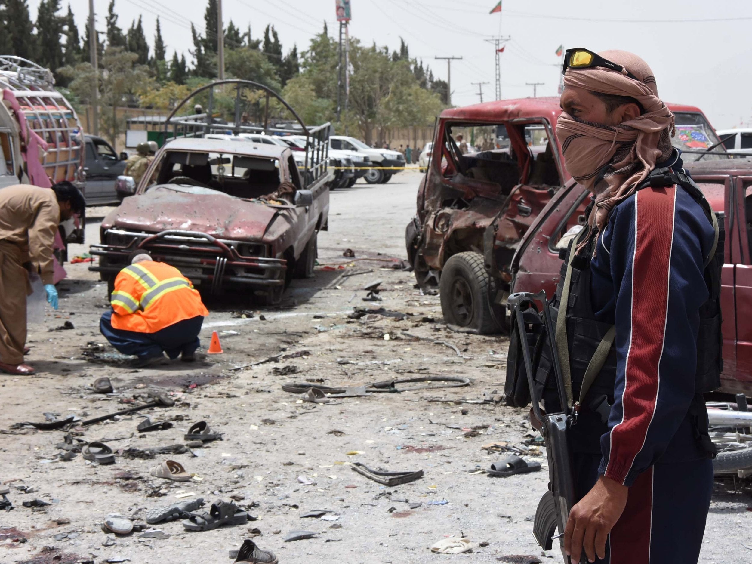 Security officials inspect the scene of a suicide bomb attack outside a polling station in Quetta