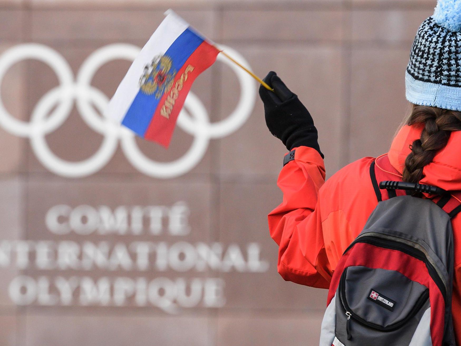 A supporter waves a Russian flag in front of the logo of the International Olympic Committee