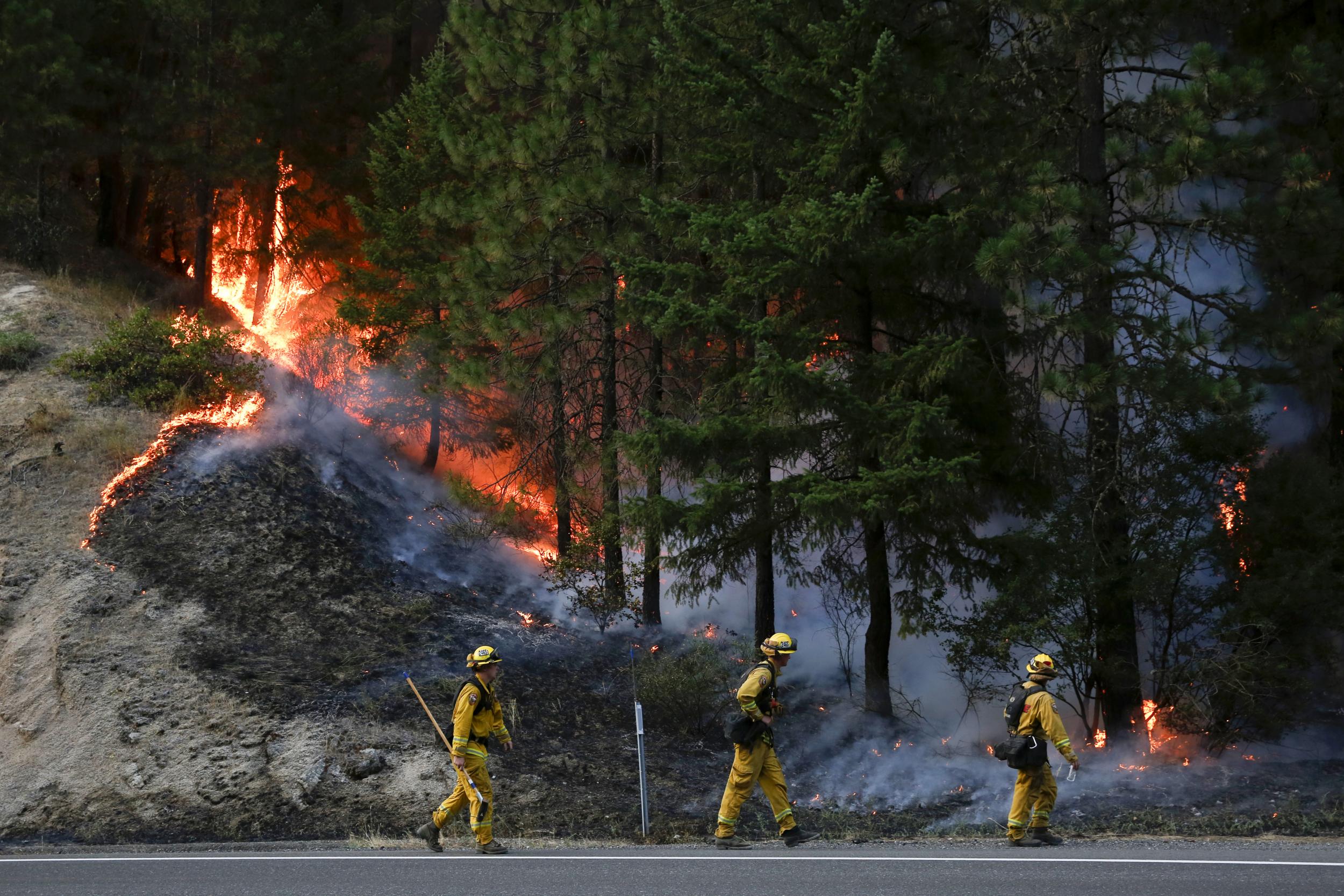 Firefighters monitor flames above State Highway 299 while battling the Carr Fire