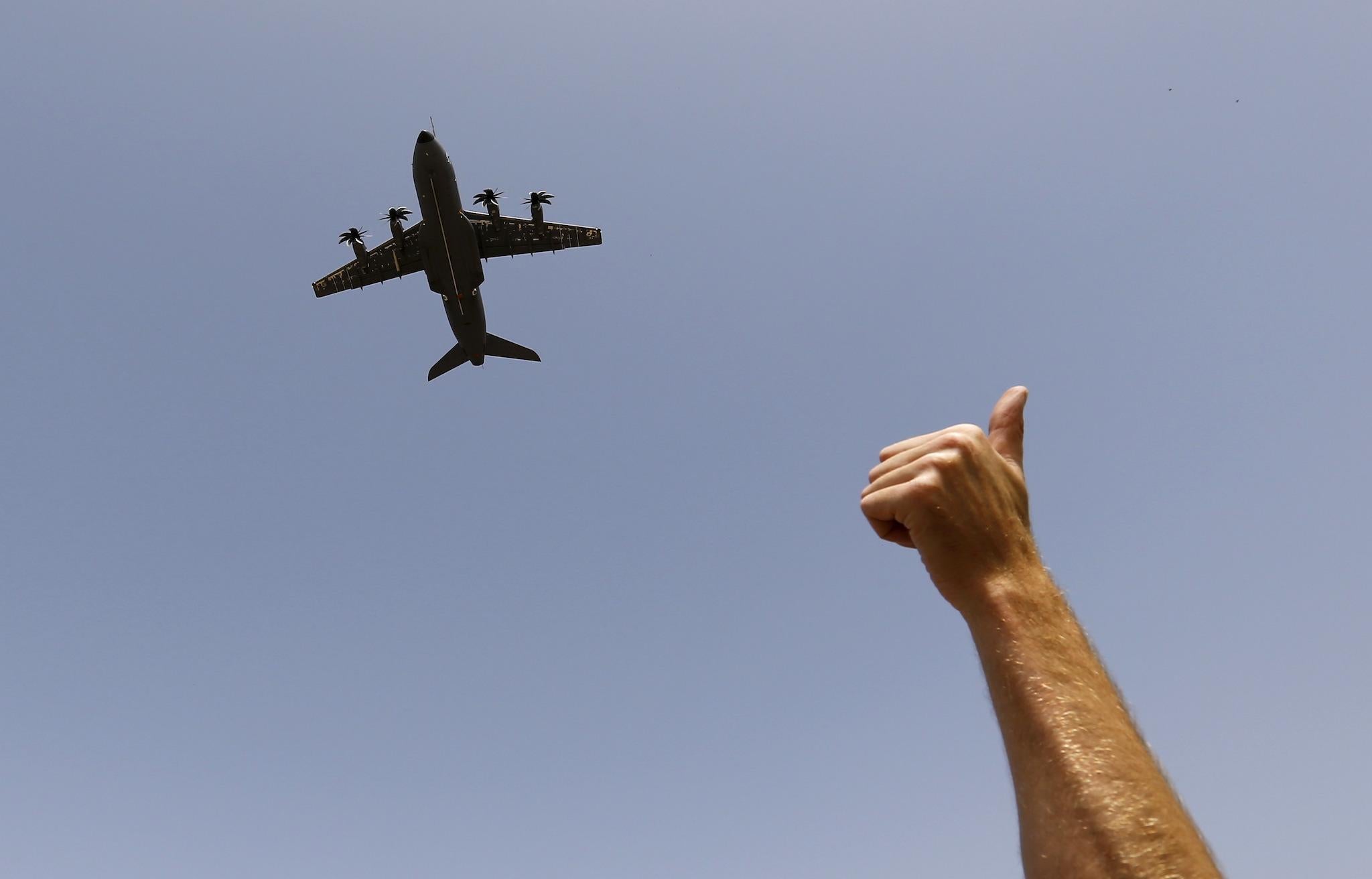 An Airbus A400M military plane flies before landing as a man gives a thumbs-up sign during a test flight at the airport of the Andalusian capital of Seville May 12, 2015