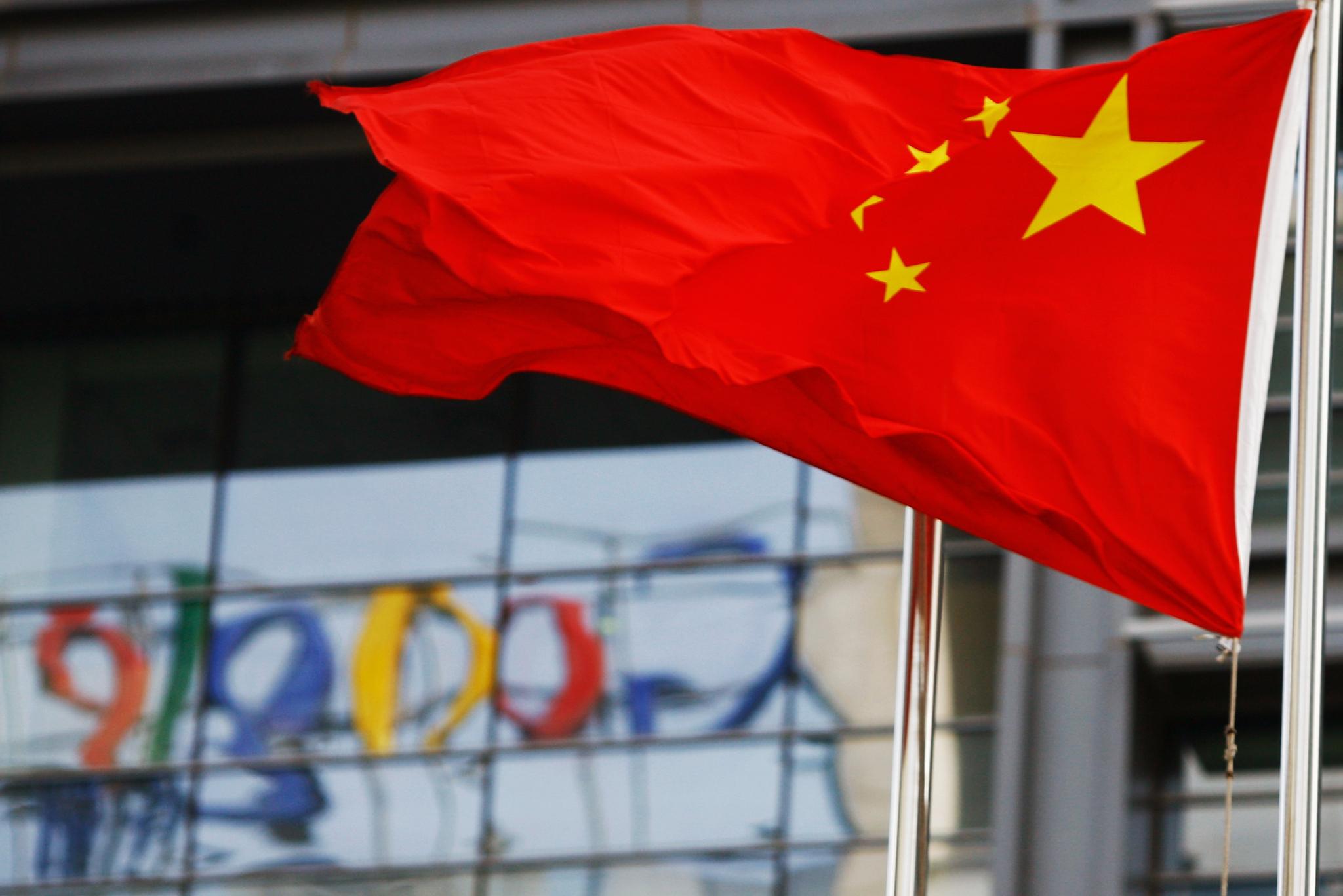 The Google logo is reflected in windows of the company's China head office as the Chinese national flag flies in the wind in Beijing on March 23, 2010