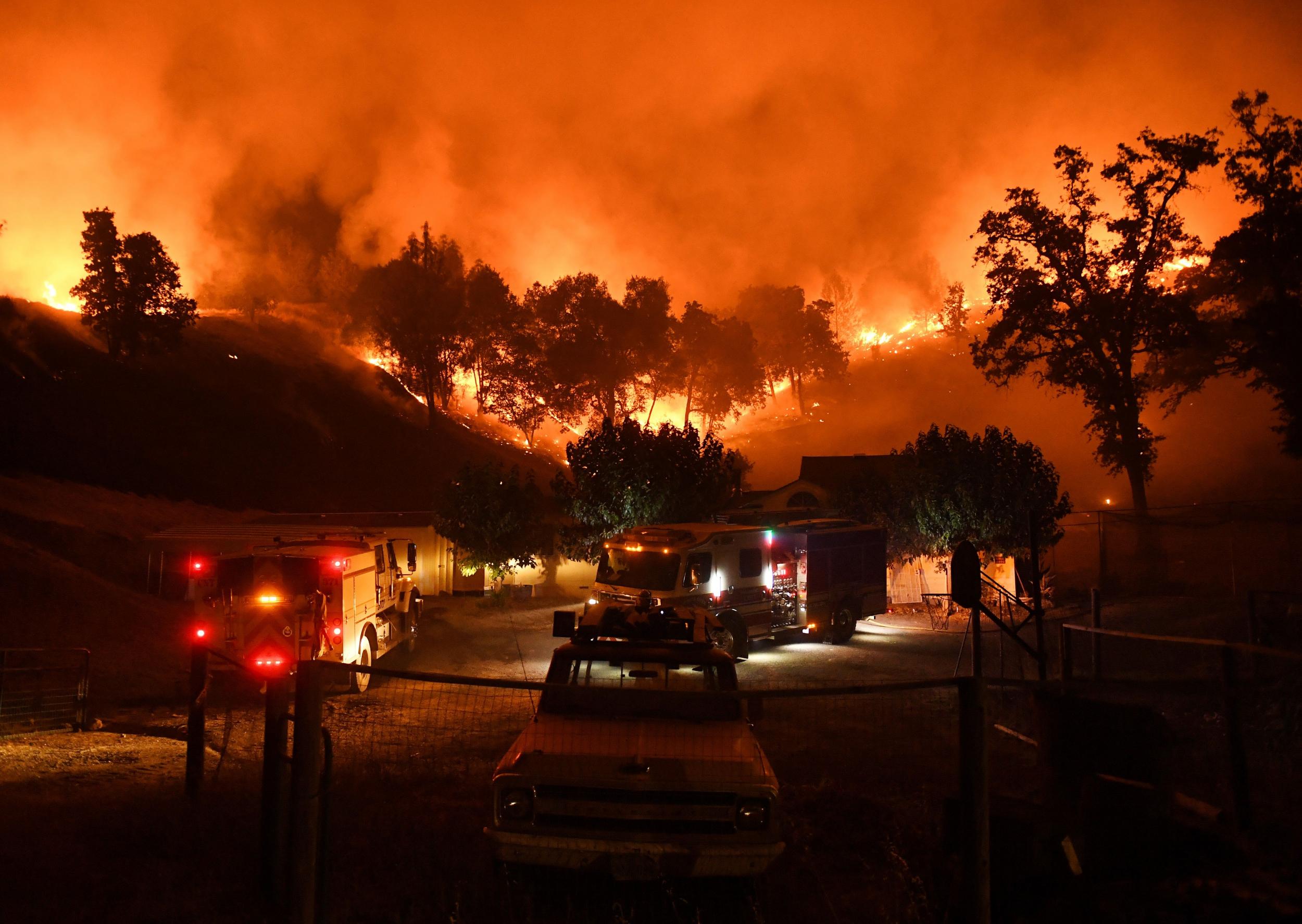 Firefighters conduct a controlled burn to defend houses against flames from the Ranch fire