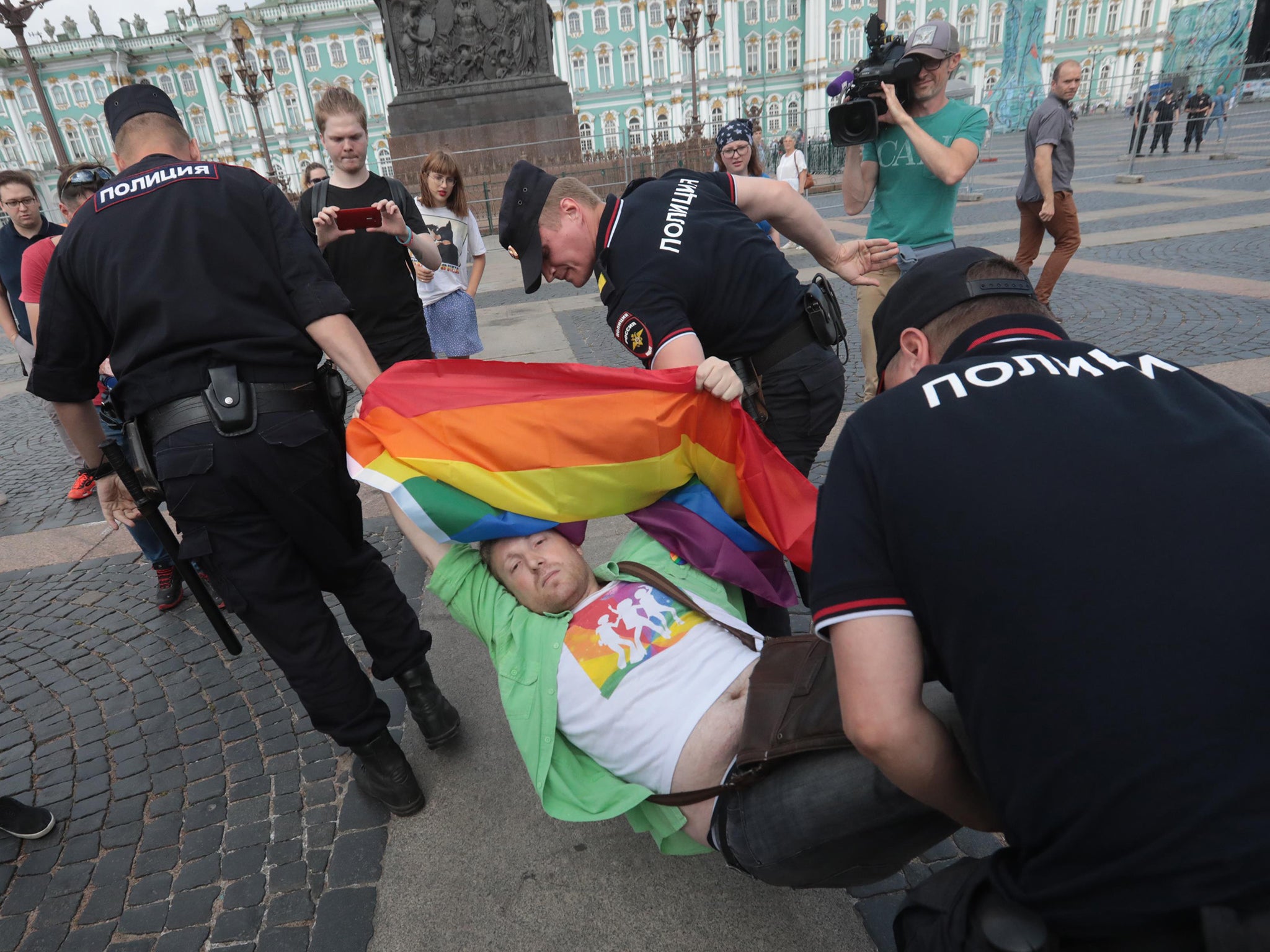 Three policemen were seen carrying one man who looked despondent but still held his multicoloured banner aloft above his head