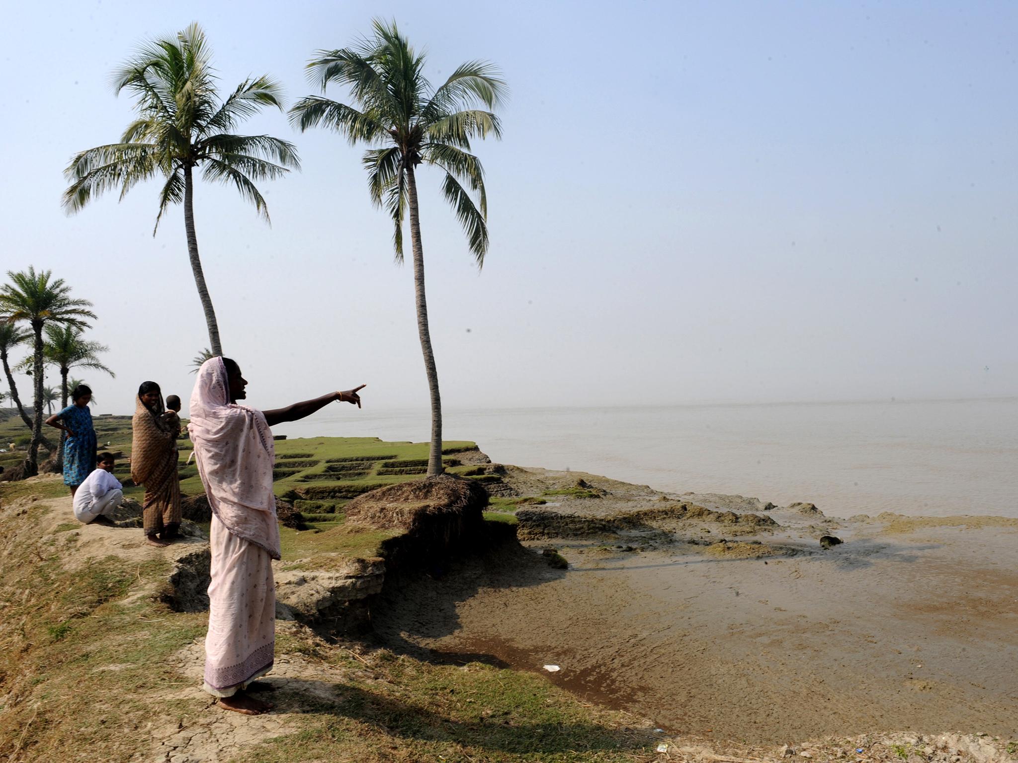 Indian villager Madhuri Sardar points at the part of the river which submerged her family's farmland 10 years ago on an island in the Sundarbans (AFP/Getty)