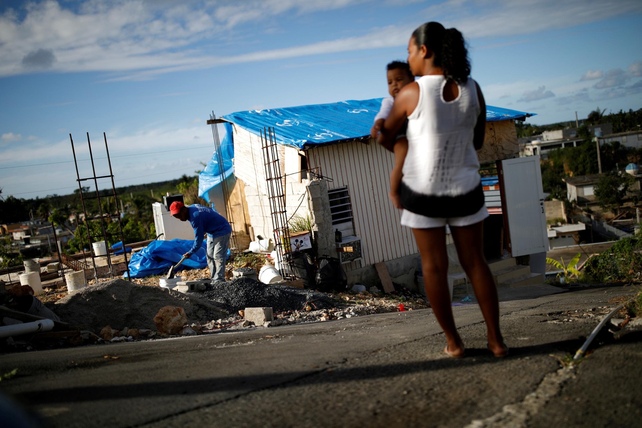 A man rebuilds his home in Villa Hugo while his wife looks on