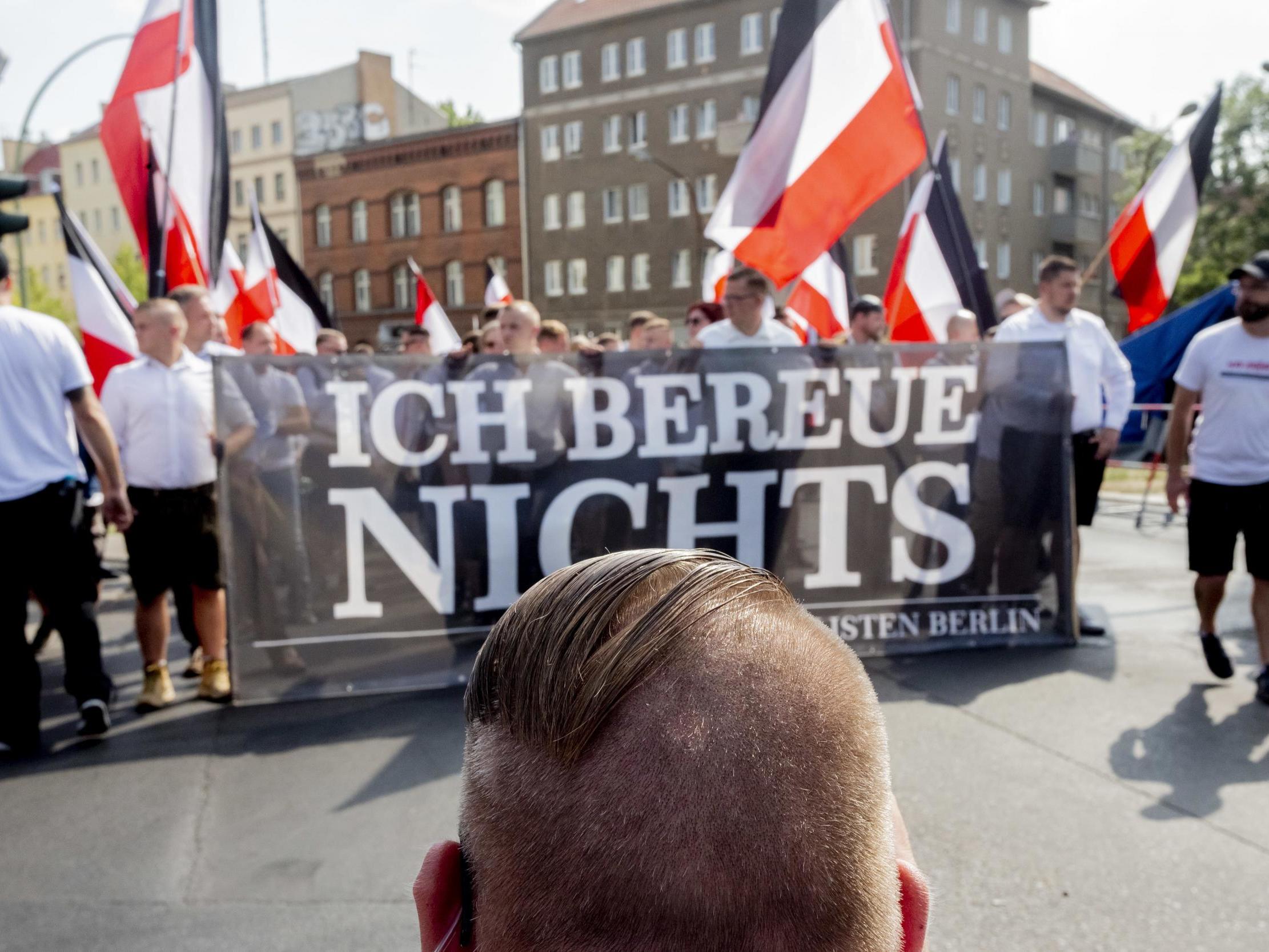 Marchers carry a banner reading 'I don't regret anything', marking the anniversary of the death of Rudolf Hess