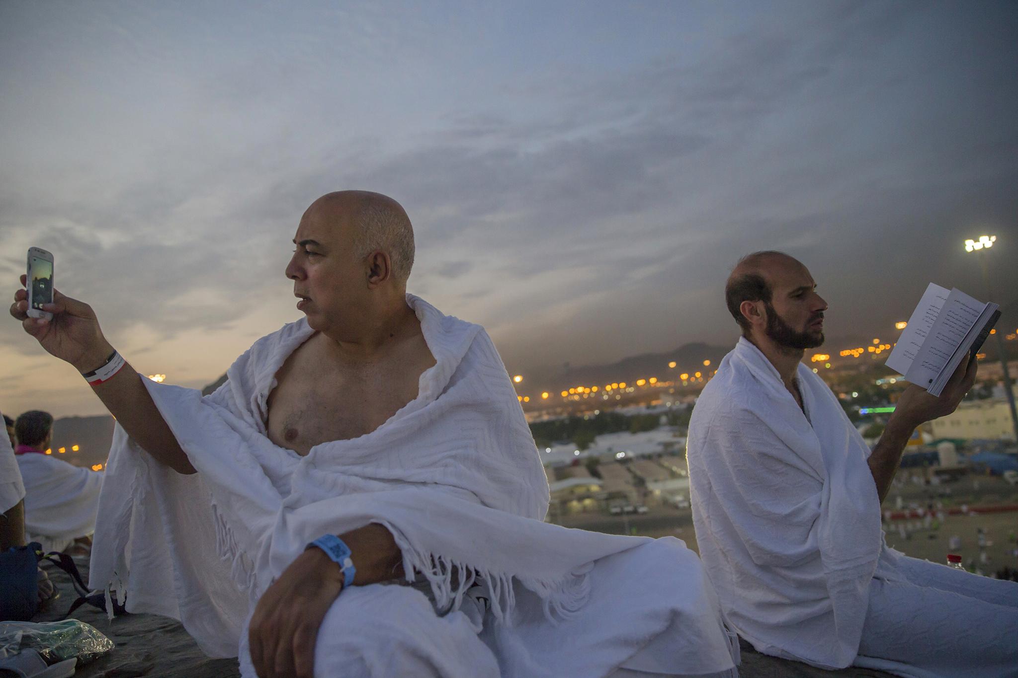 A Muslim pilgrim prays as another takes a photo on the Mount Arafat
