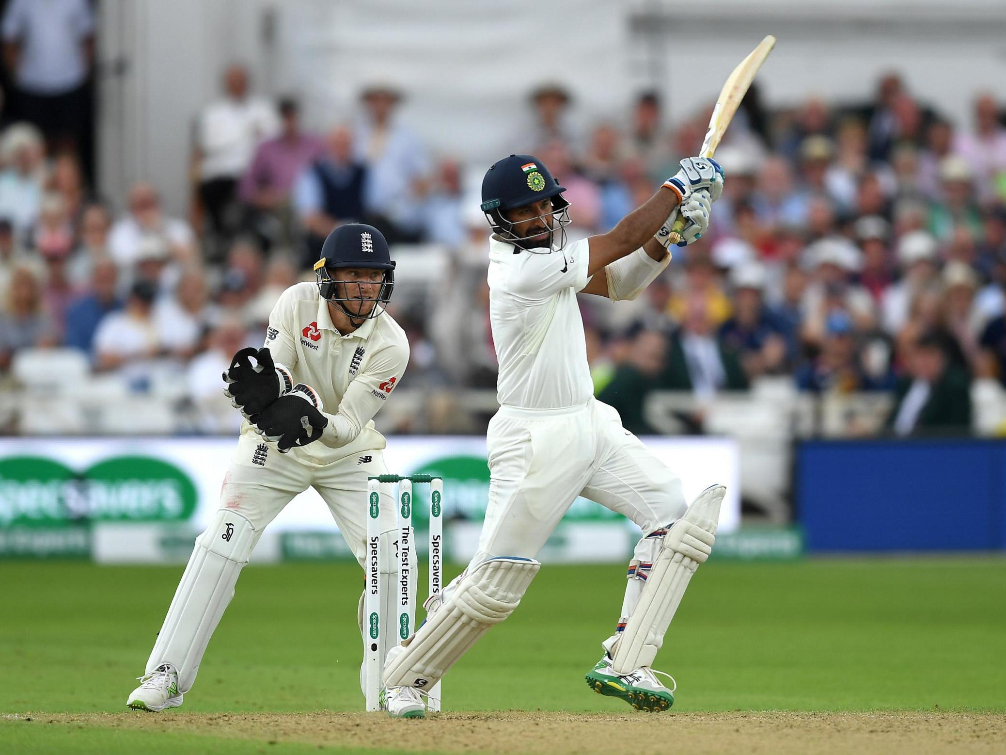 Cheteshwar Pujara hits a shot as Jos Buttler looks on