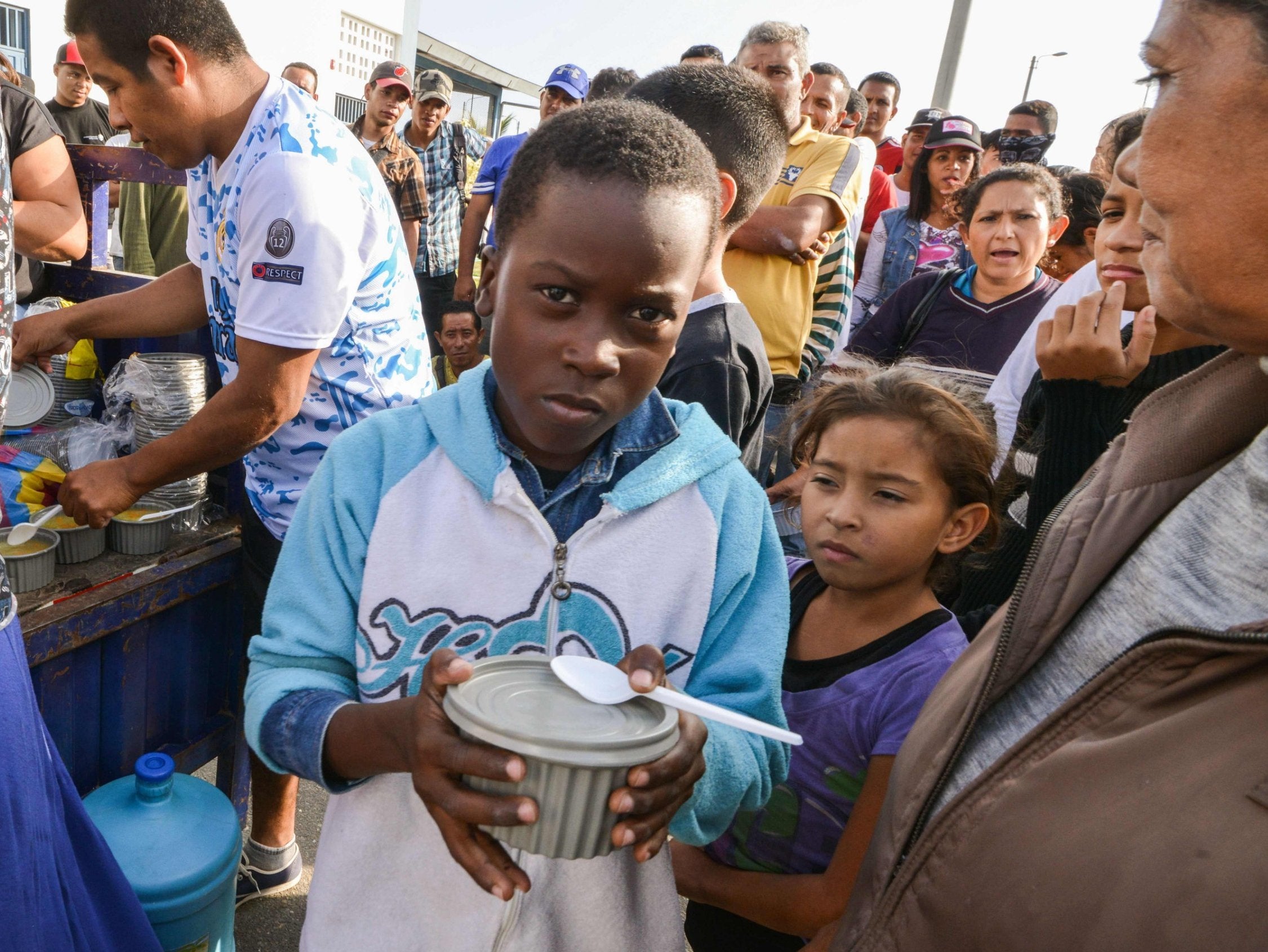 Venezuelan nationals receive food from religious volunteers while they wait for an authorisation that will allow them to enter Peru.