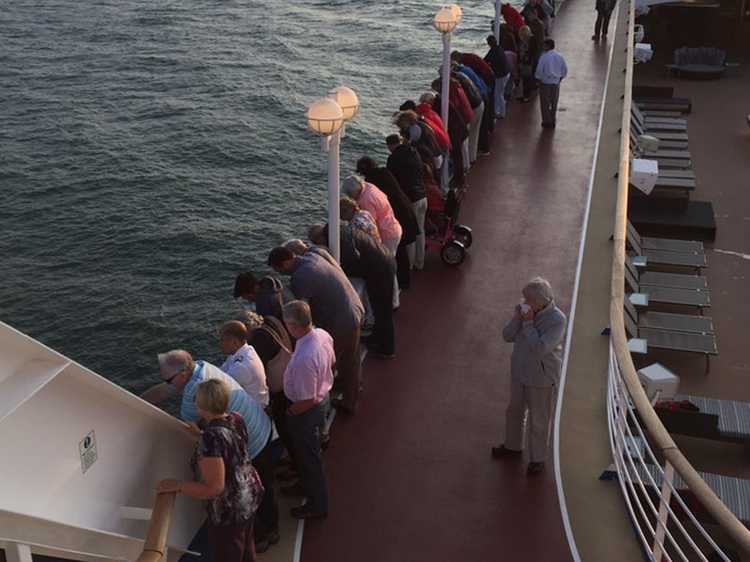 Passengers look on as the three rescued fishermen make their way on to the cruise ship