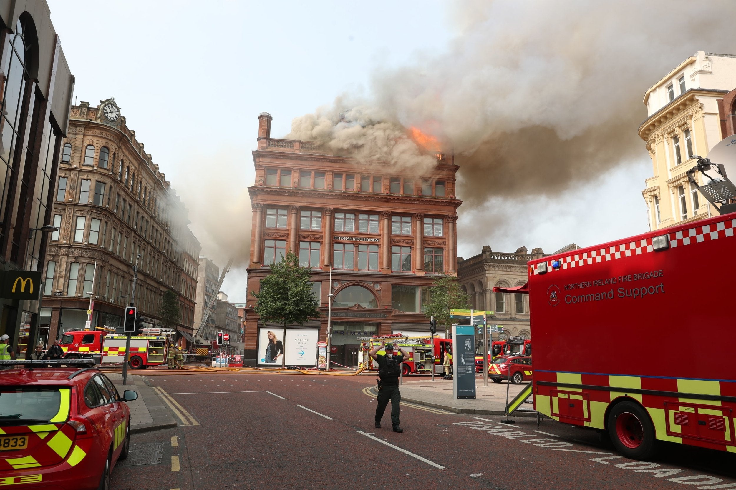 A police officer urges people to keep back as fire crews tackle a blaze at Primarkin Belfast