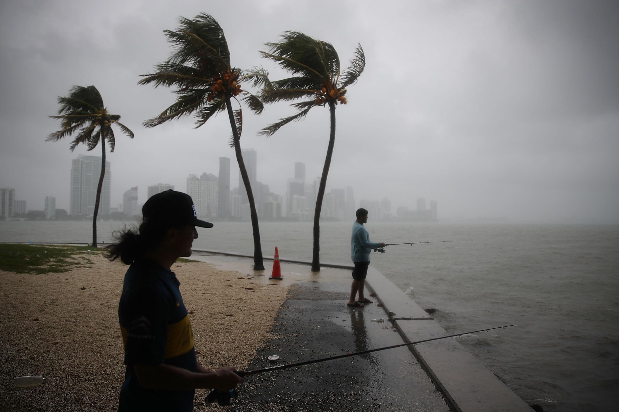 Walter Augier (L) and Jhon M. fish as rain and wind are whipped up by Tropical Storm Gordon