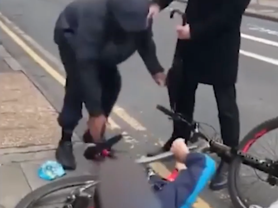 The man clings to his bike despite being punched in the face