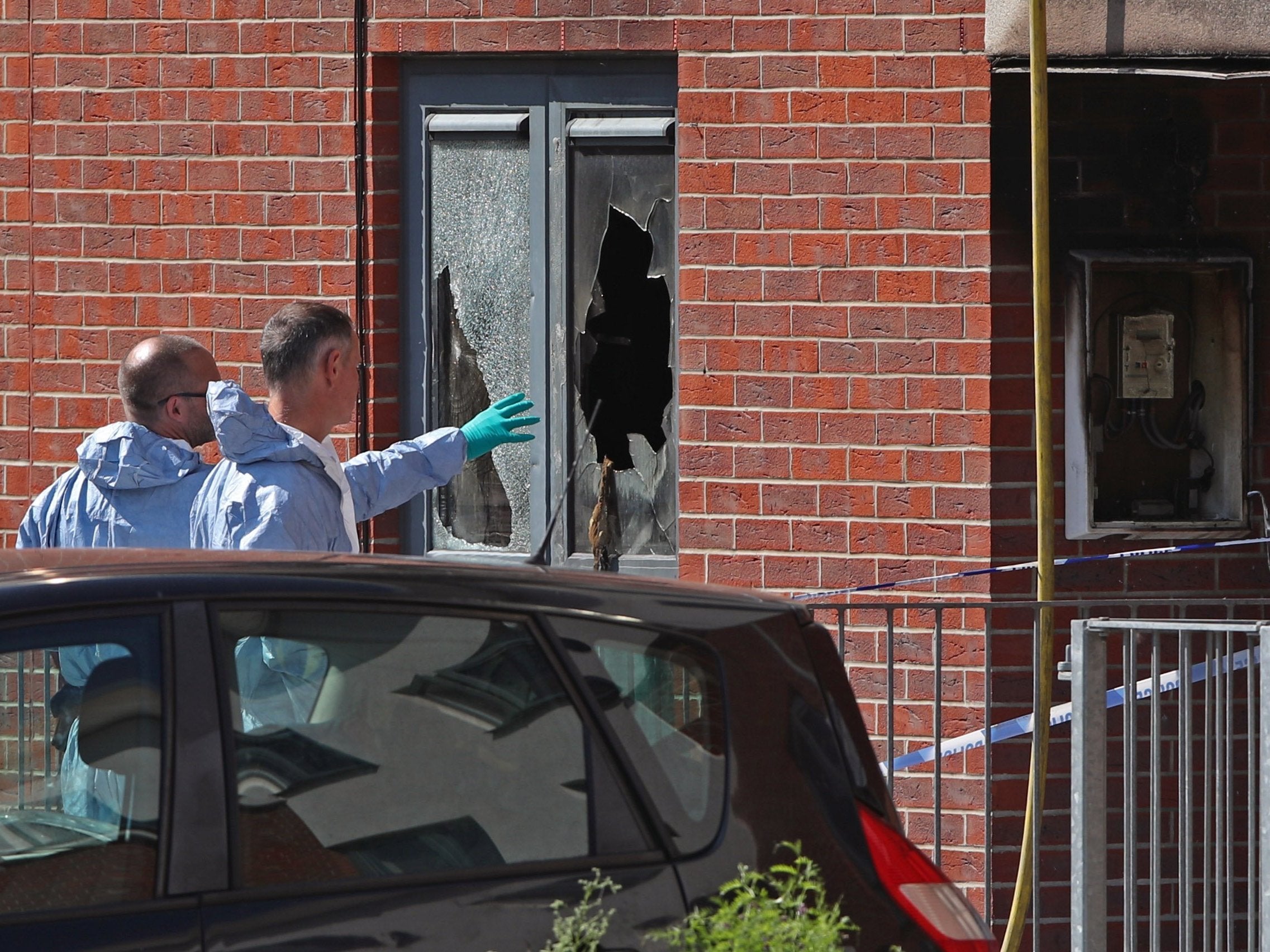 Forensics officers comb the fire-ravaged building for clues