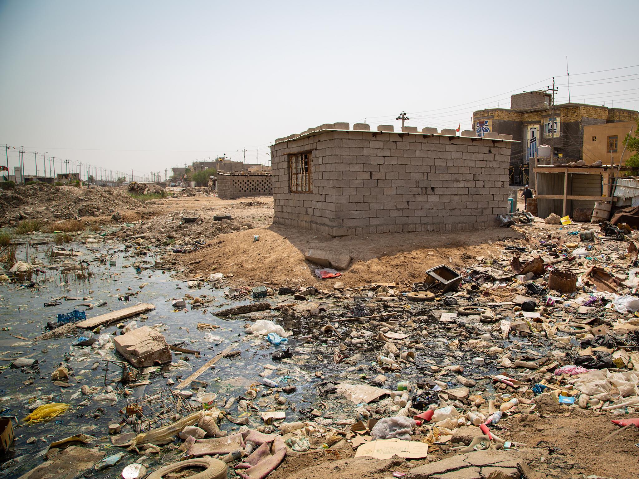 Breeze-block homes overlook swamp of sewage and rubbish in rundown districts of Basra, where residents have no water