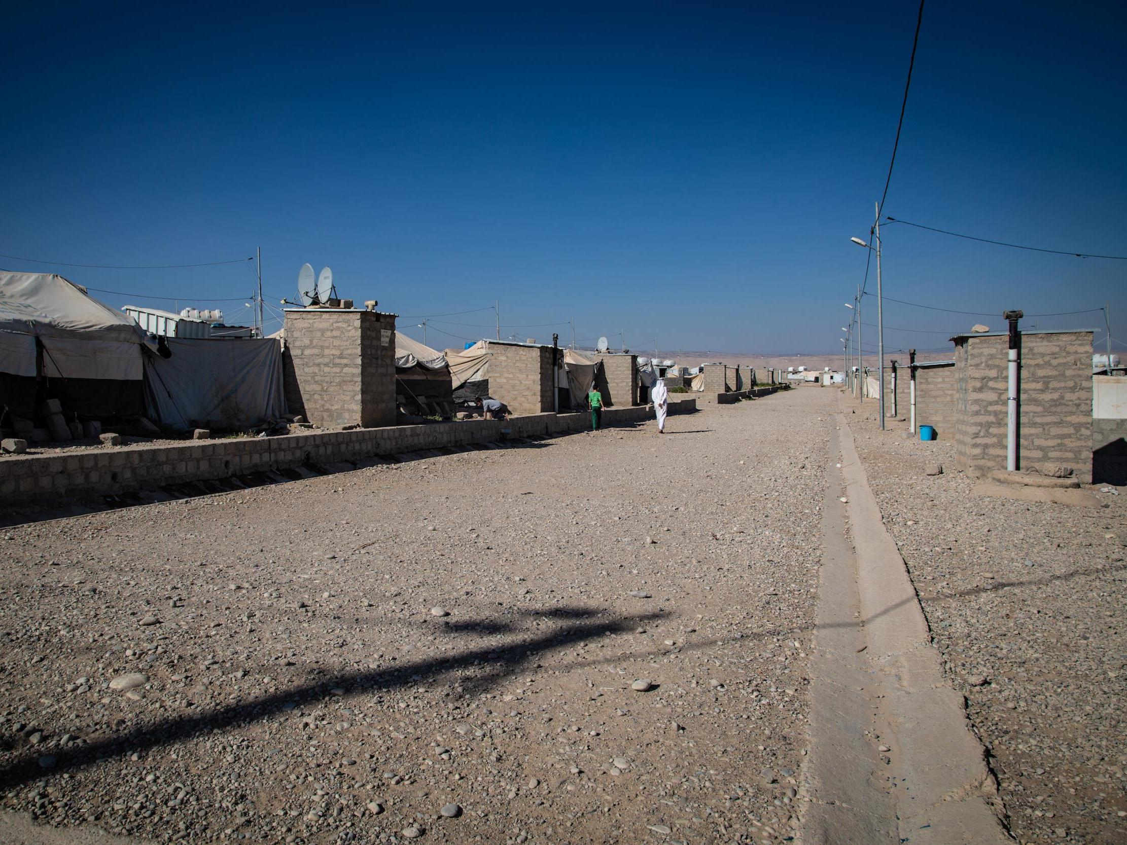 Residents of Gamawa camp walk past tents where over 100 families have lived for nearly two years since fleeing the Mosul offensive against Isis