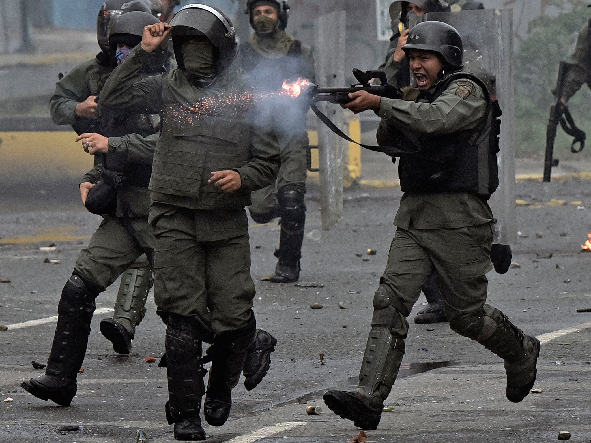 A member of the national guard fires a shotgun at opposition demonstrators during clashes in Caracas last year