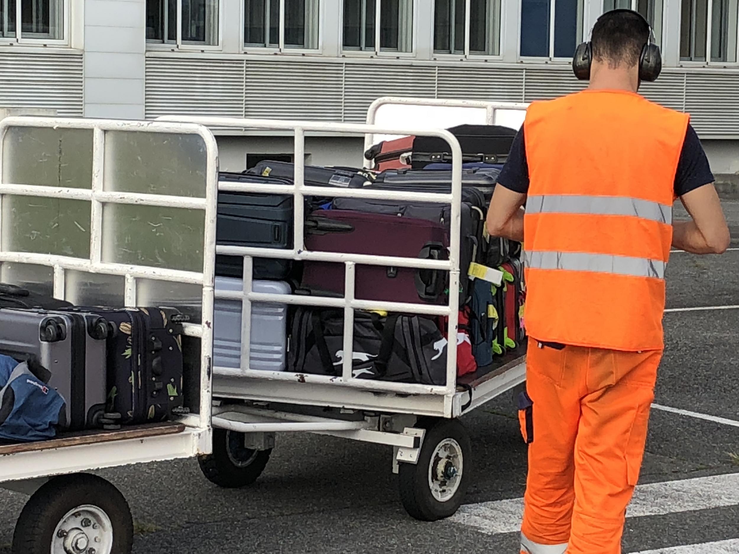 A baggage handler loads luggage into a plane