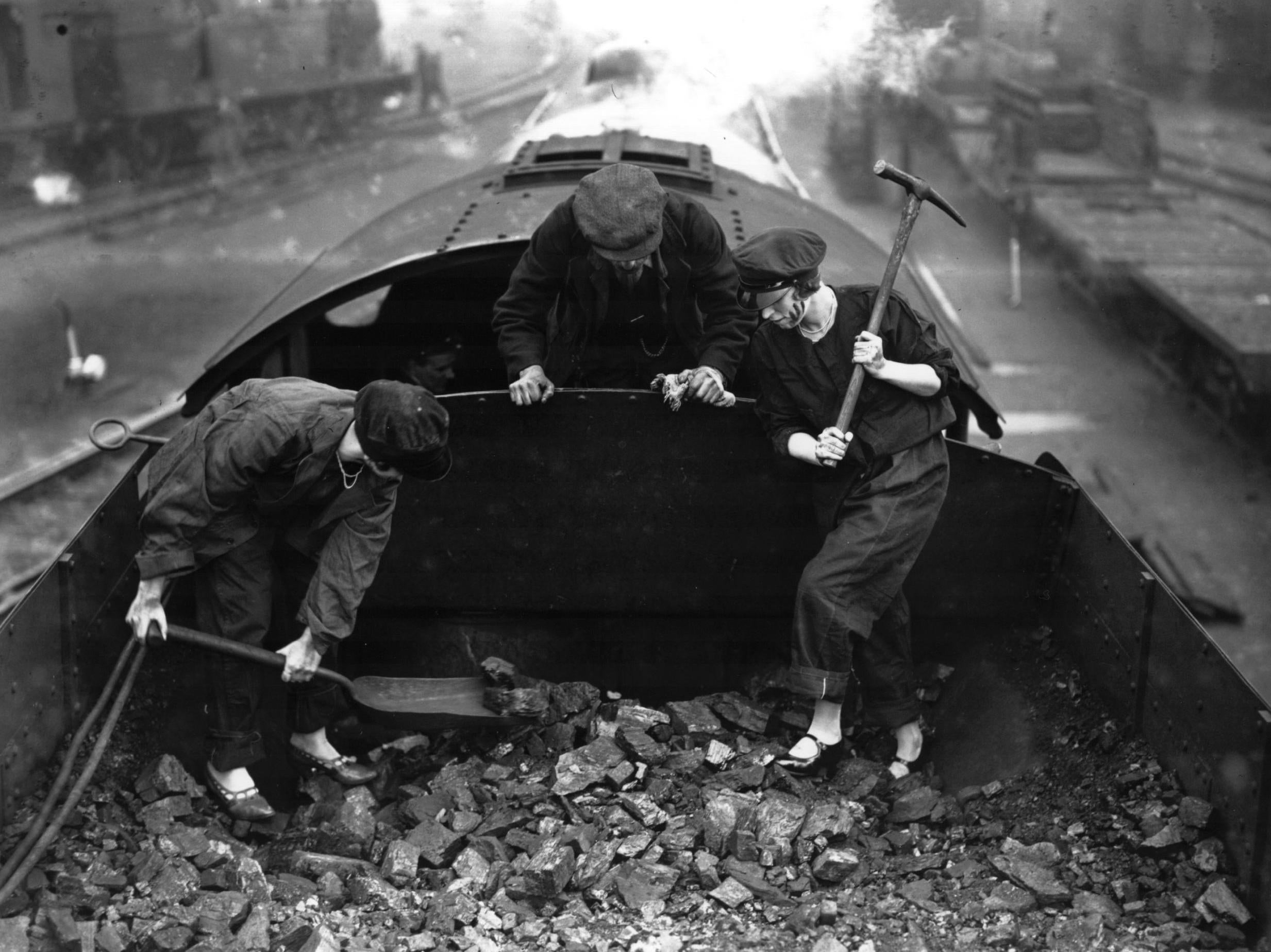 Lady engine drivers, in light shoes, turn their hands to shovelling coal on a steam engine during the general strike