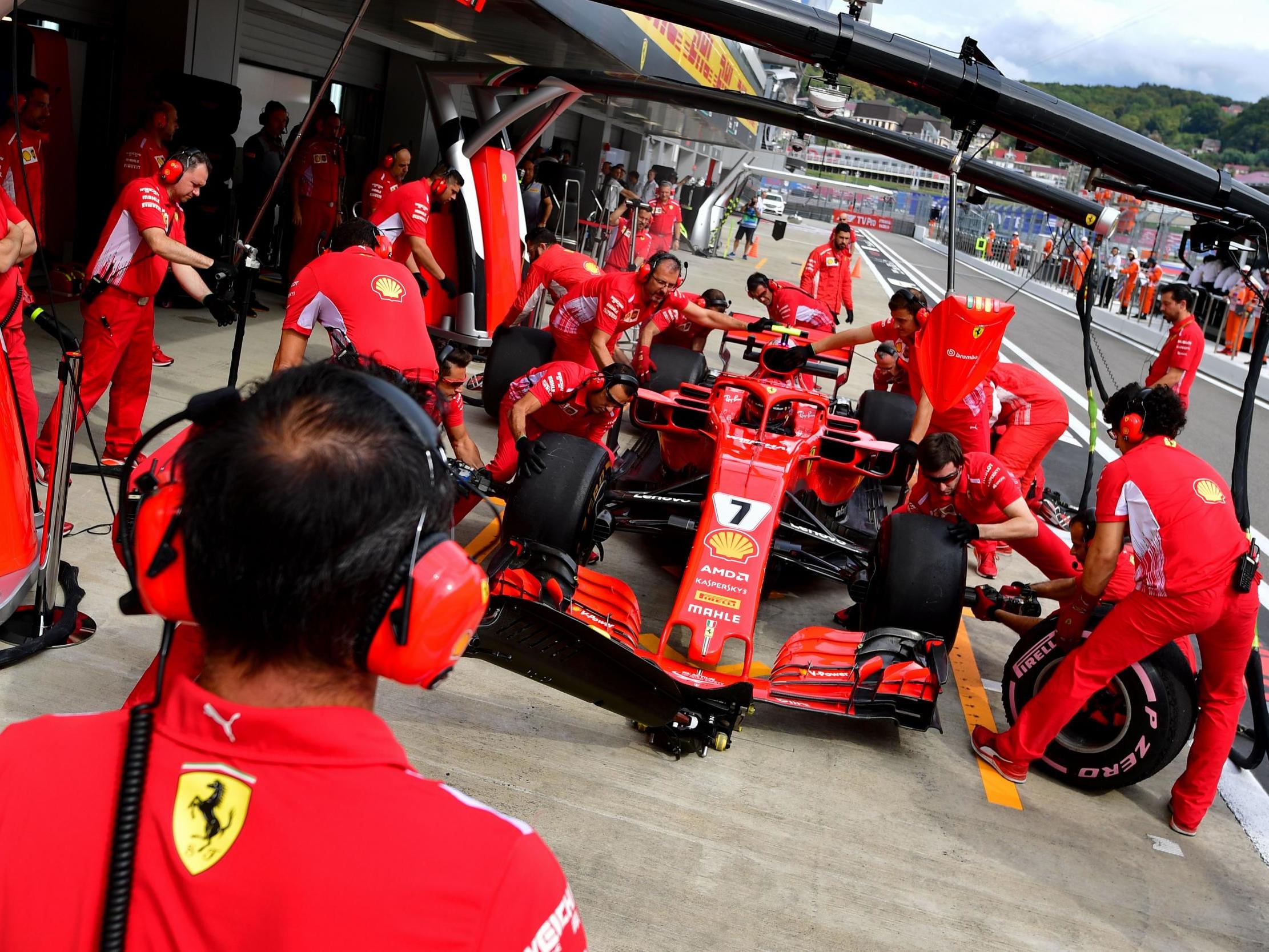 Kimi Raikkonen has his car worked on by mechanics during a pit stop