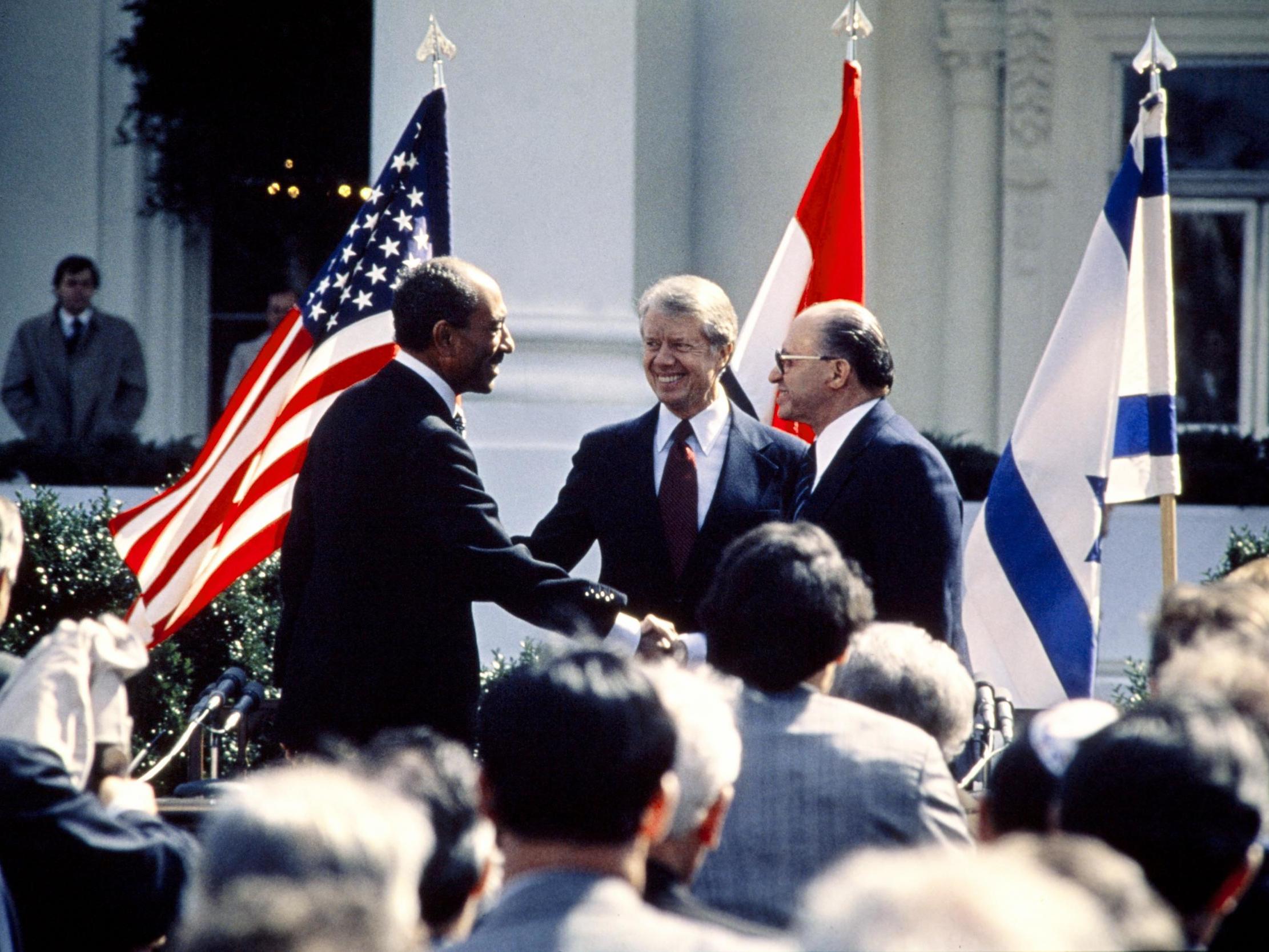 US president Jimmy Carter congratulates Egyptian president Anwar al-Sadat and Israeli premier Menachem Begin as they shake hands on 26 March 1979 on the north lawn of the White House, Washington DC