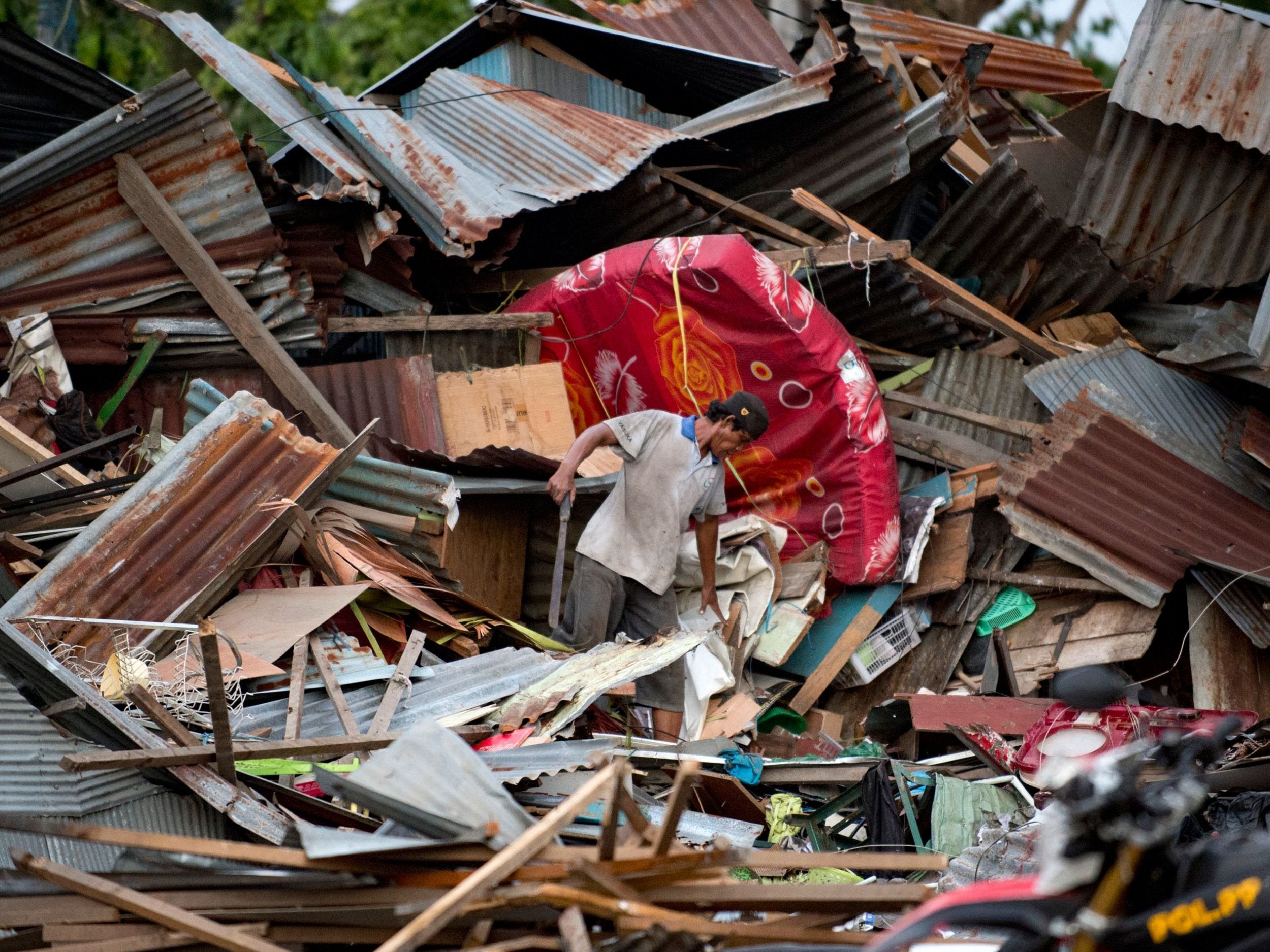 A man looks for his belongings amid the debris of his destroyed house in Palu