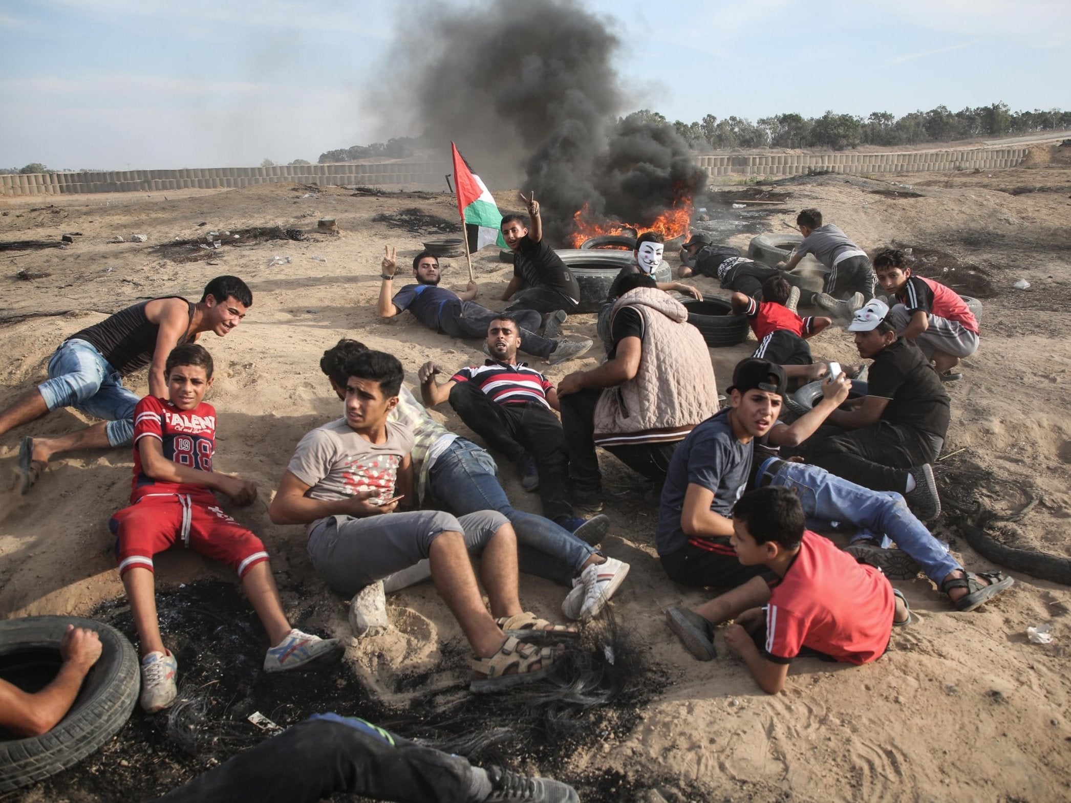 Palestinian protesters take cover as Israeli security forces use tear gas to disperse them during a demonstration near Al Bureij Refugee Camp on the Gaza-Israel border, 5 October