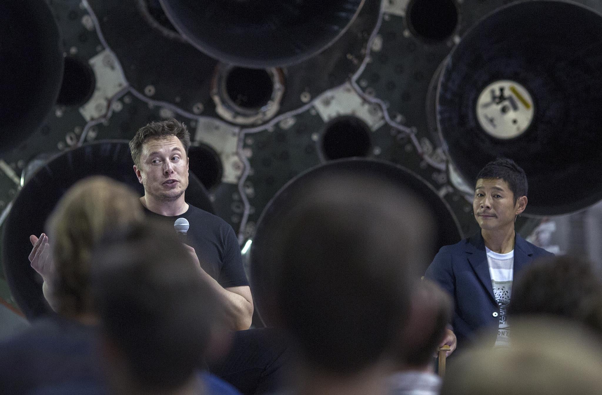 Elon Musk (L) and Japanese billionaire Yusaku Maezawa speak before a Falcon 9 rocket during the announcement that Maezawa will be the first private passenger who will fly around the Moon