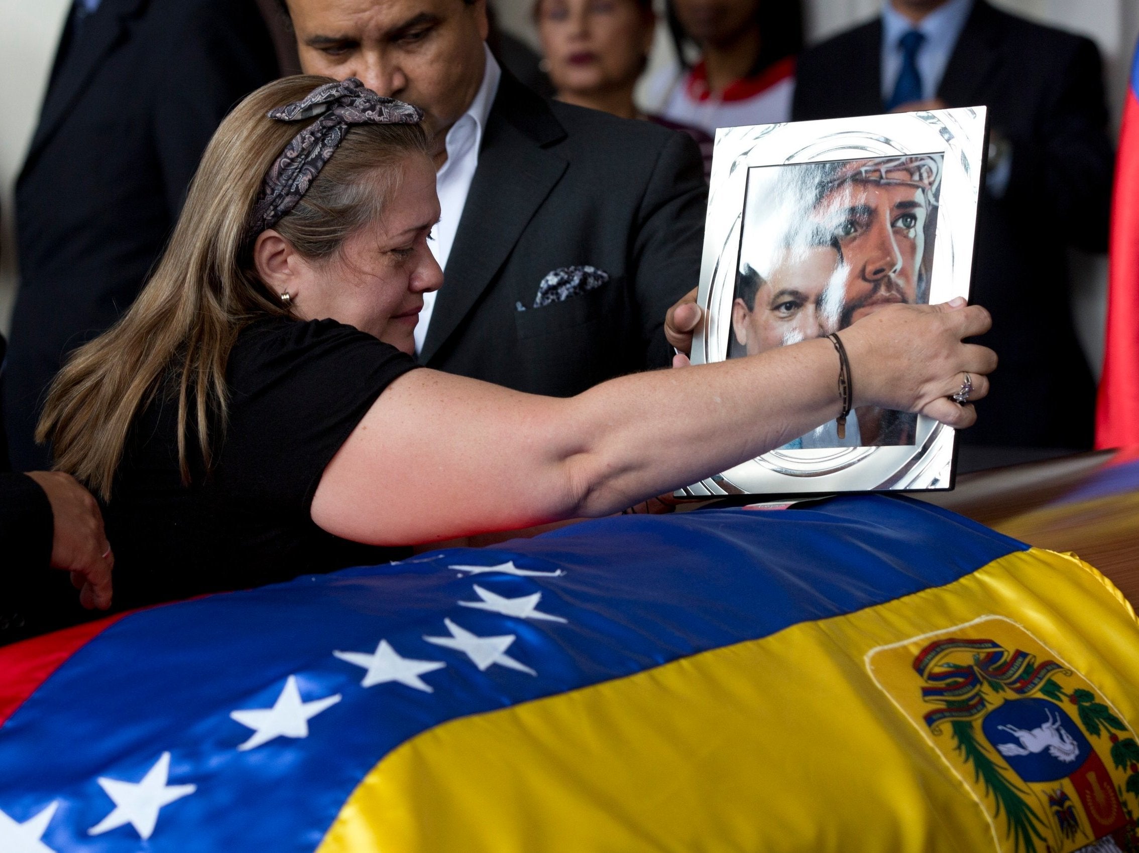 Luz Alban, the sister of opposition activist Fernando Alban places a framed portrait of her brother