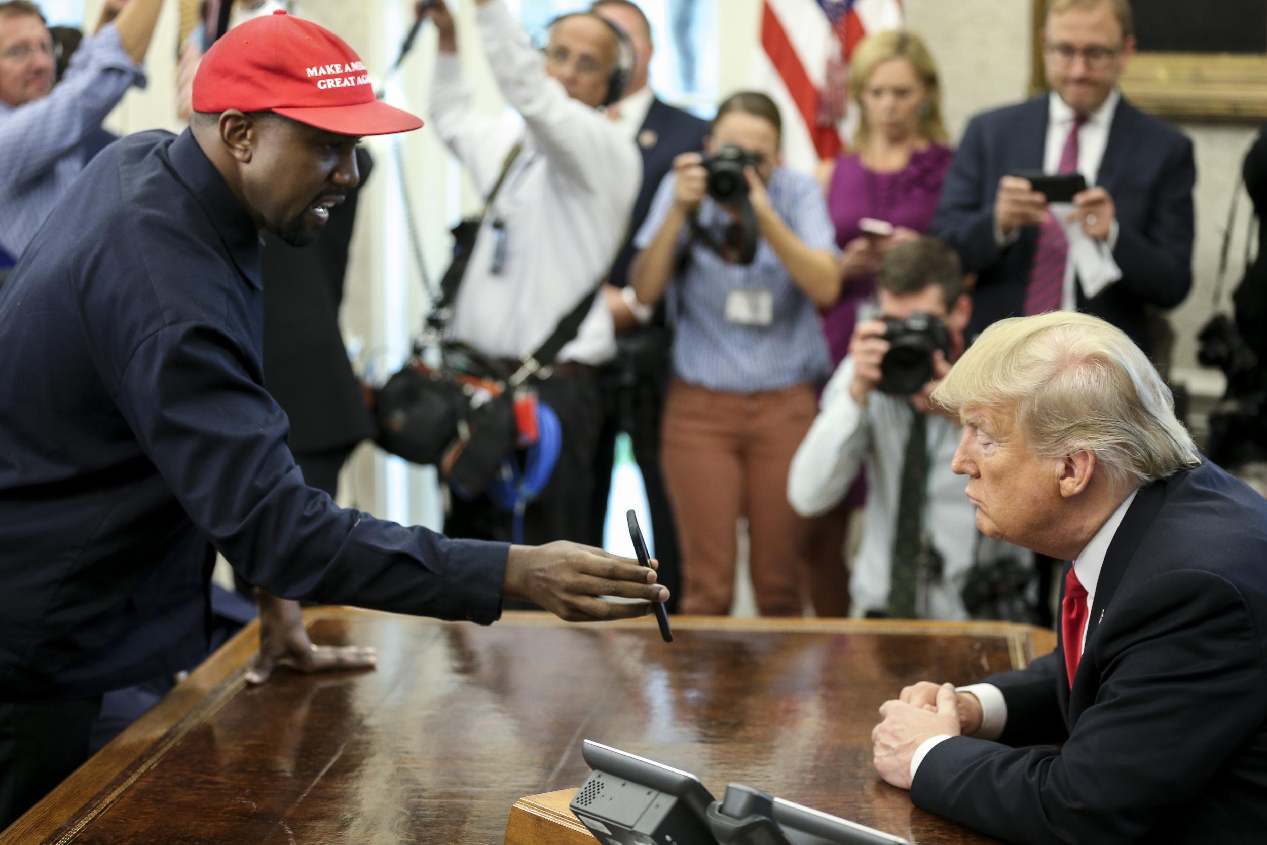 Kanye West shows a picture of a plane to Donald Trump during a meeting in the Oval office of the White House in 2018