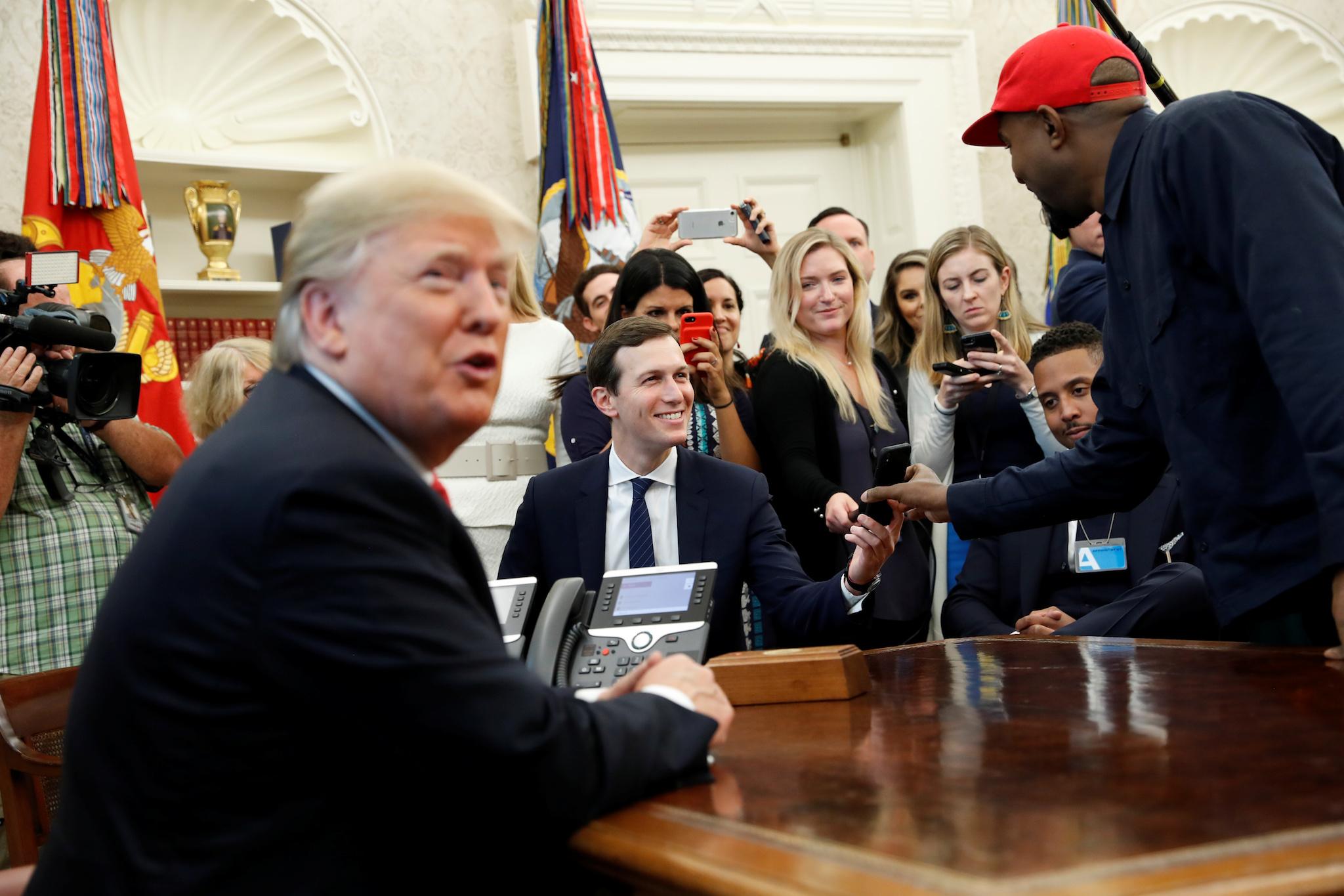 Rapper Kanye West shows a photo on his mobile phone to White House senior adviser Jared Kushner during a meeting with U.S. President Donald Trump