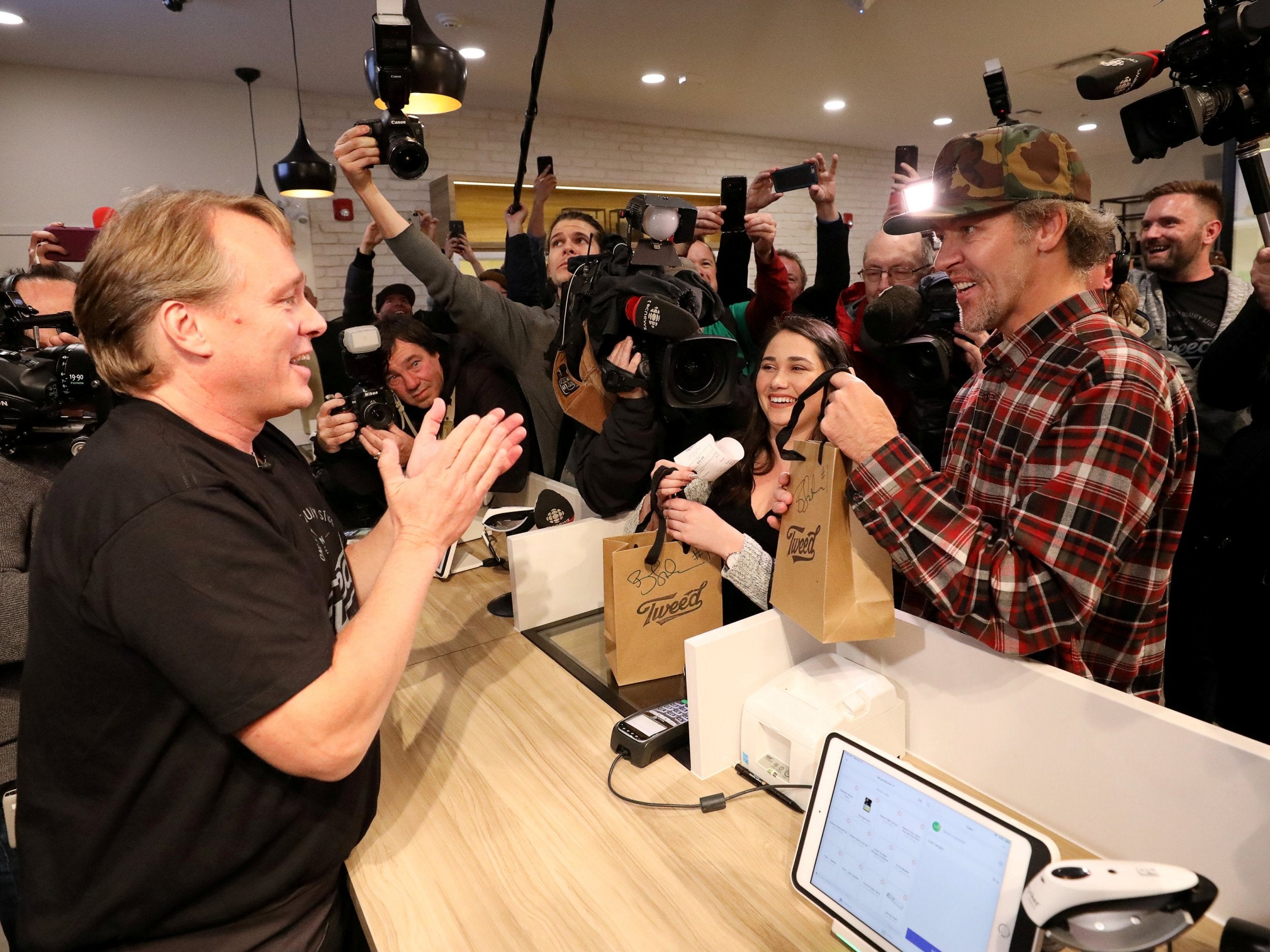Canopy Growth CEO Bruce Linton hands Ian Power and Nikki Rose the first legal recreational marijuana purchases after midnight at a store in St John's, Newfoundland and Labrador, Canada