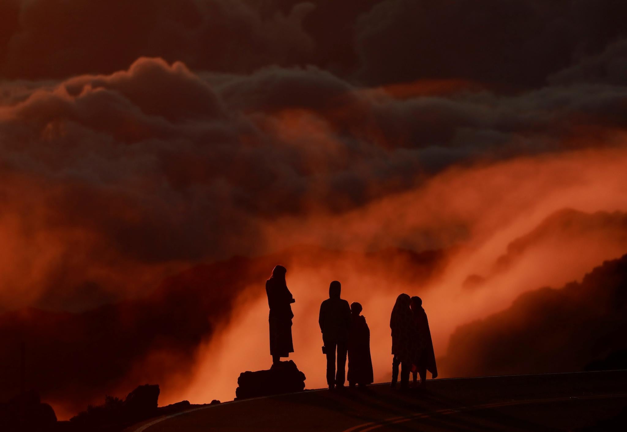 Light illuminates clouds as people watch the sunrise at Haleakala National Park in Hawaii