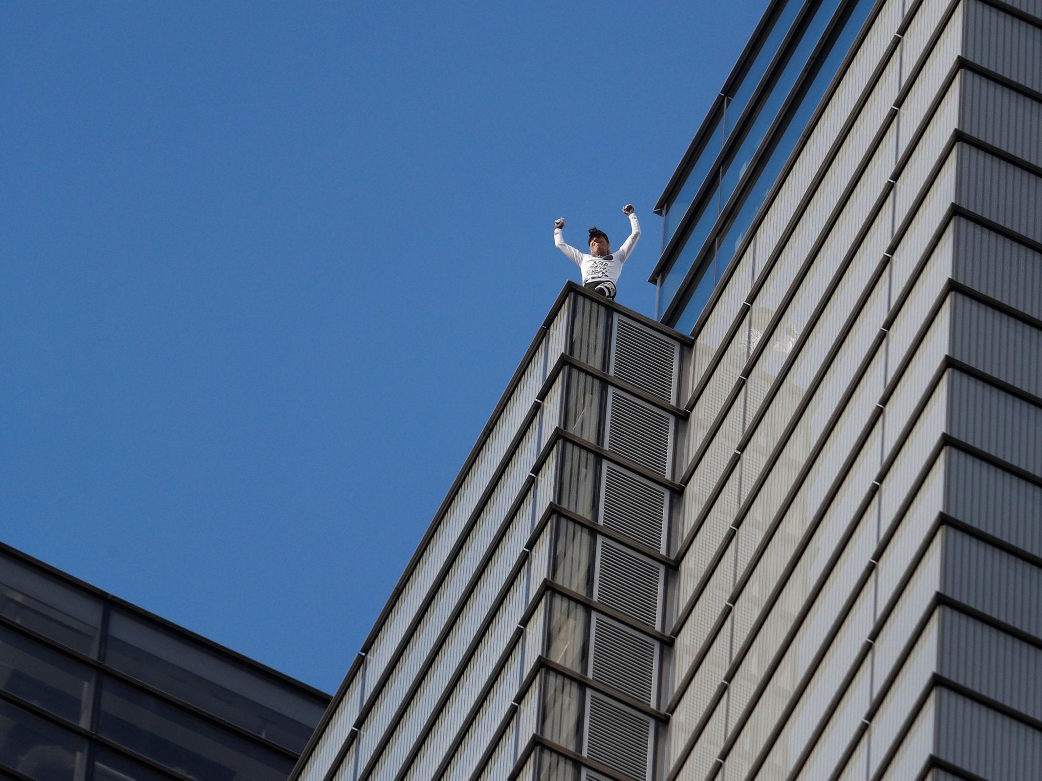 Alain Robert celebrates as he completes his climb up the outside of the Heron Tower