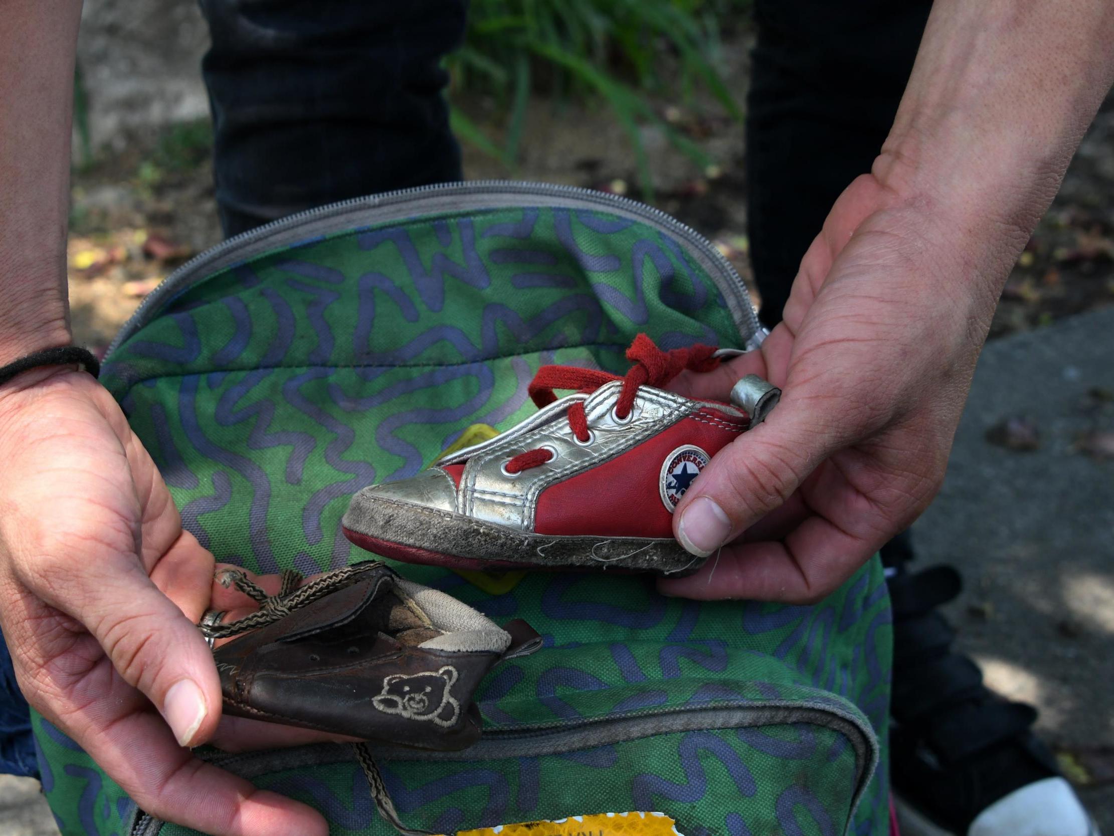 A man shows two little shoes belonging to his eight-month old daughter after being separated from his family, locked up in a Texan detention centre and deported to San Pedro Sula (Photo by ORLANDO SIERRA /