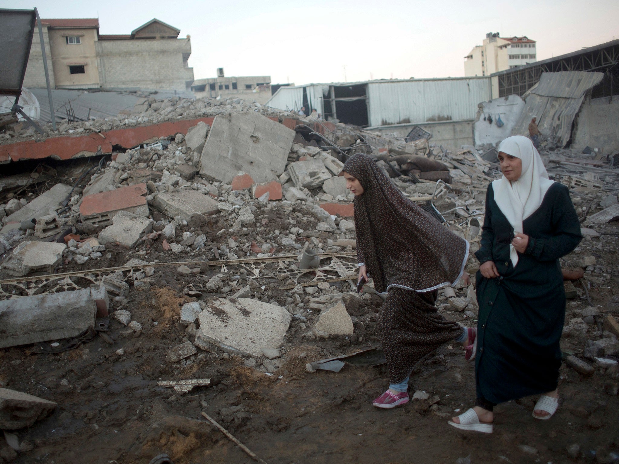 Palestinian women walk past buildings levelled by Israeli airstrikes in Gaza City on 27 October