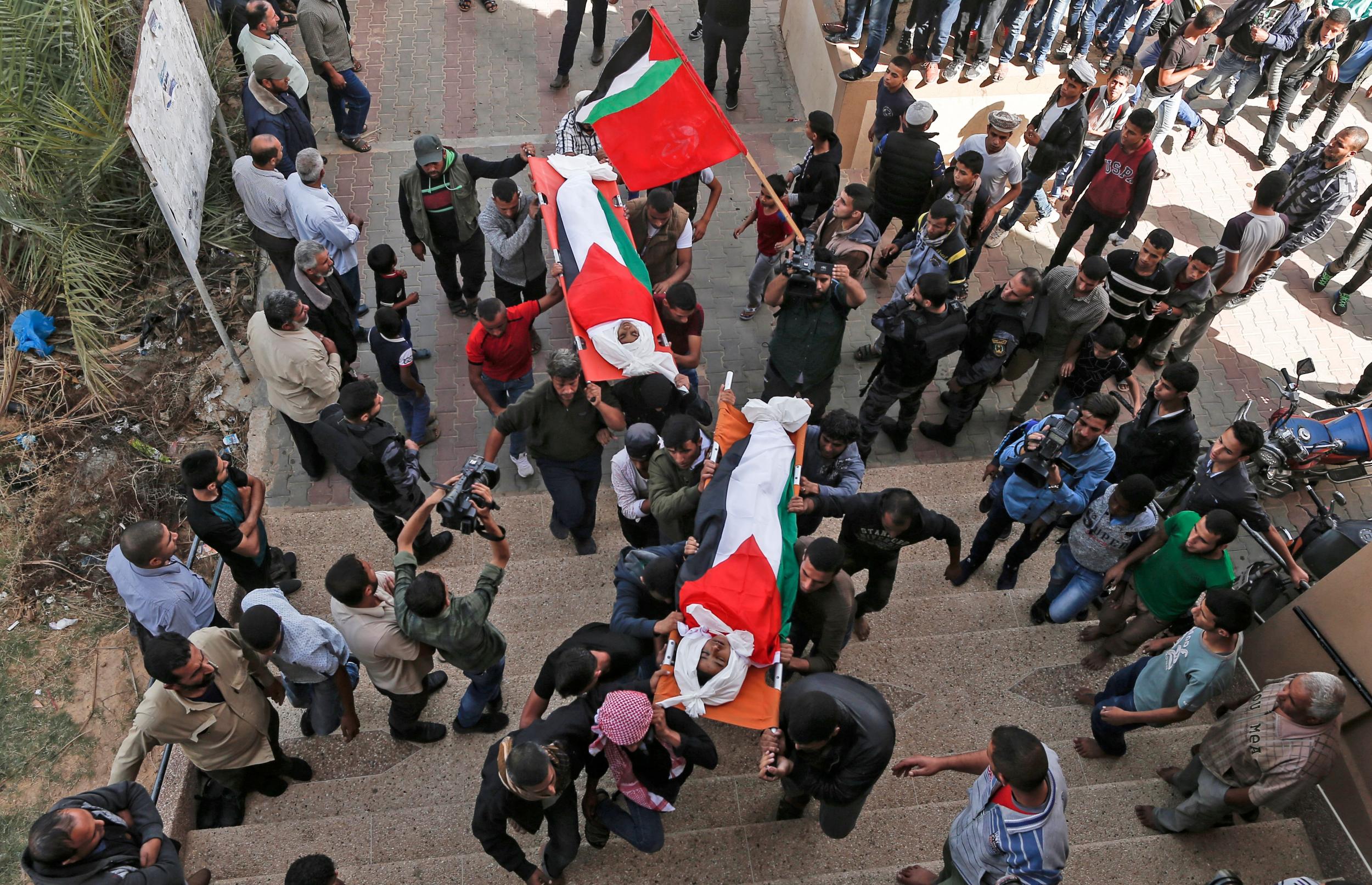 Palestinian mourners carry the bodies, draped in their national flag, of two of the three teenagers who were killed in an Israeli strike during their funeral in Deir el-Balah in the central Gaza Strip