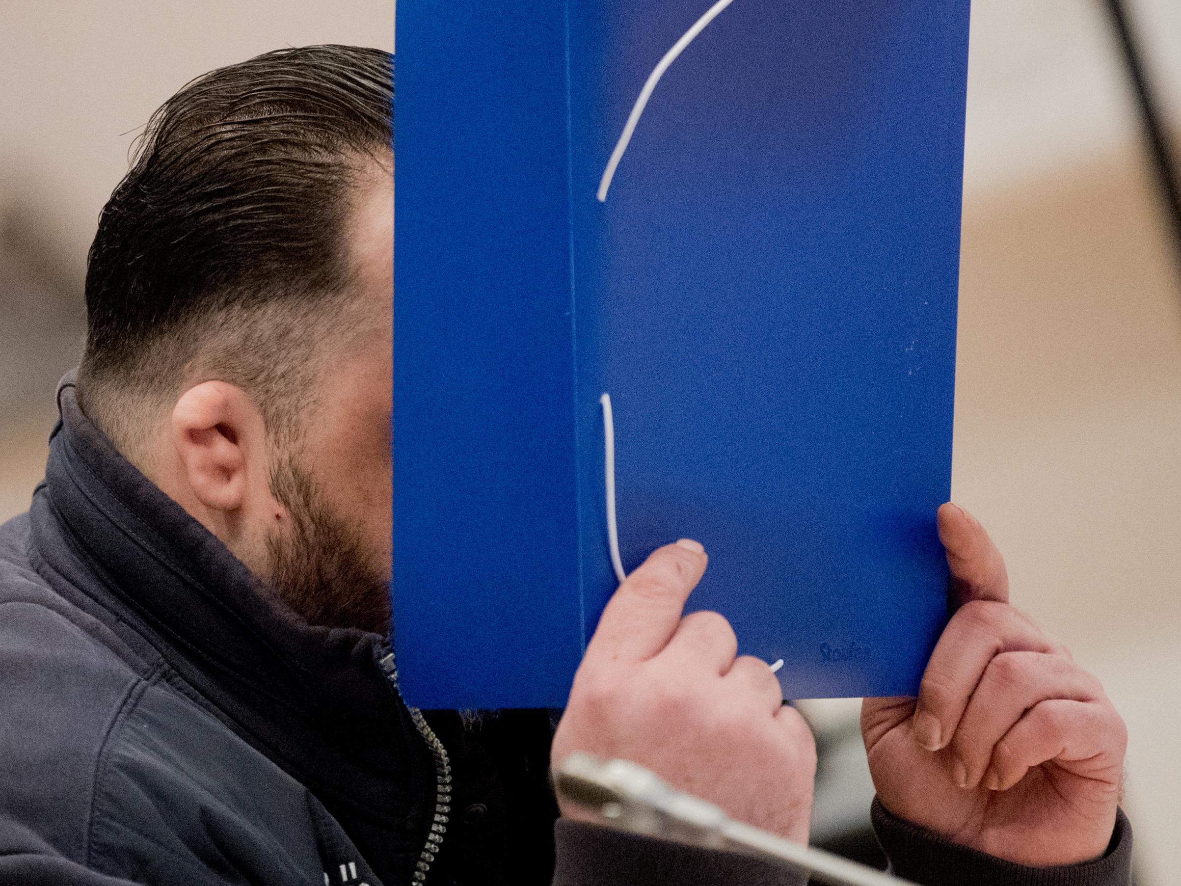 Niels Hoegel covers his face as a he arrives for his trial at a court in Oldenburg, Germany