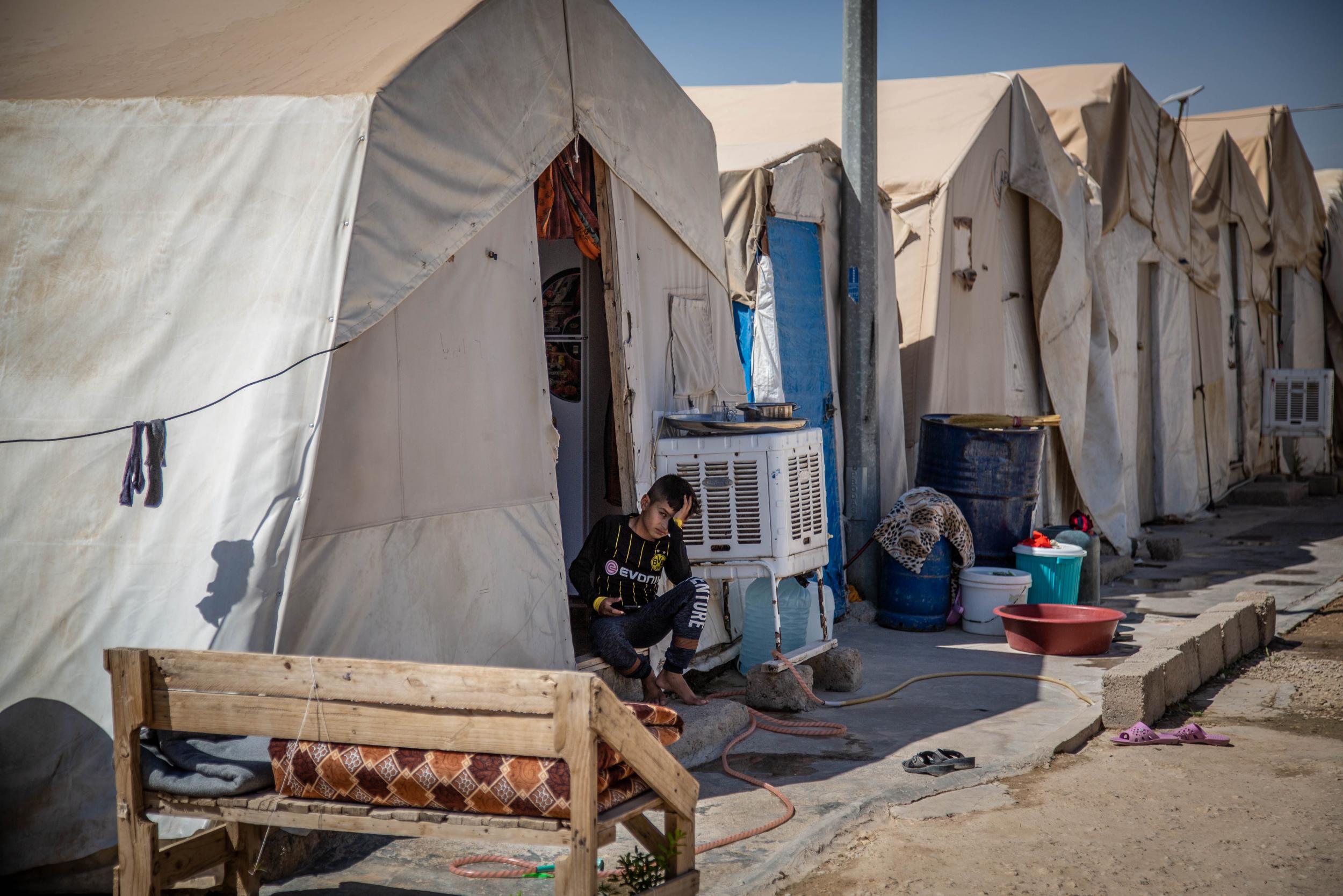 A young Yazidi boy sits outside his tent in a displacement camp Duhok, Iraqi Kurdistan