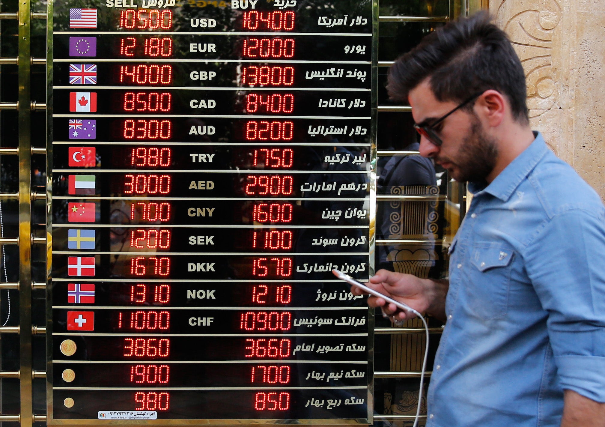 An Iranian checks the currency rates