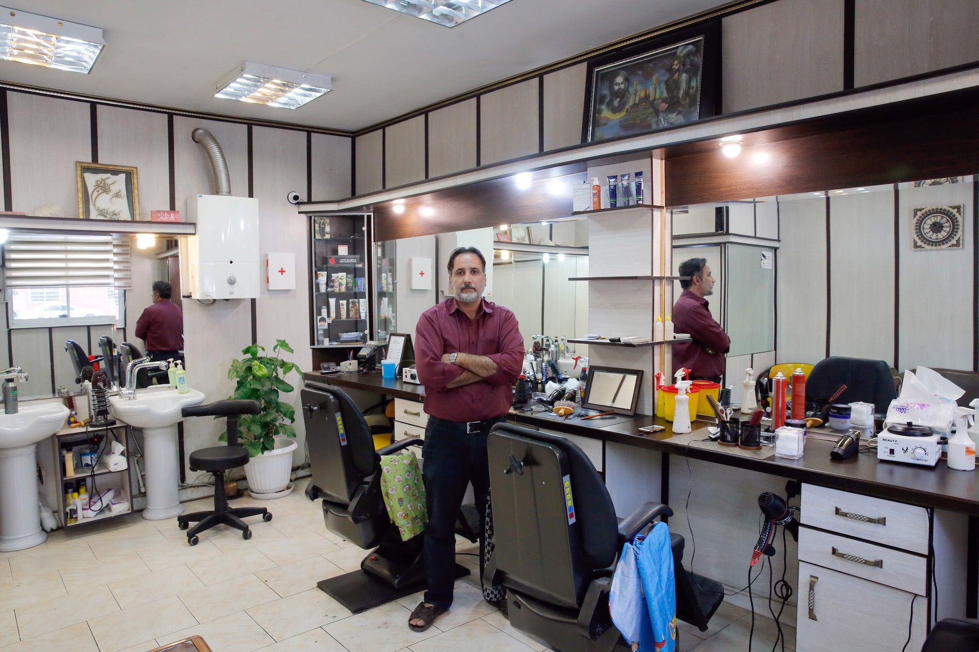 An Iranian barber in his empty barbershop in Tehran, complaining that some days he has no customers because people prefer to spend only on essential services