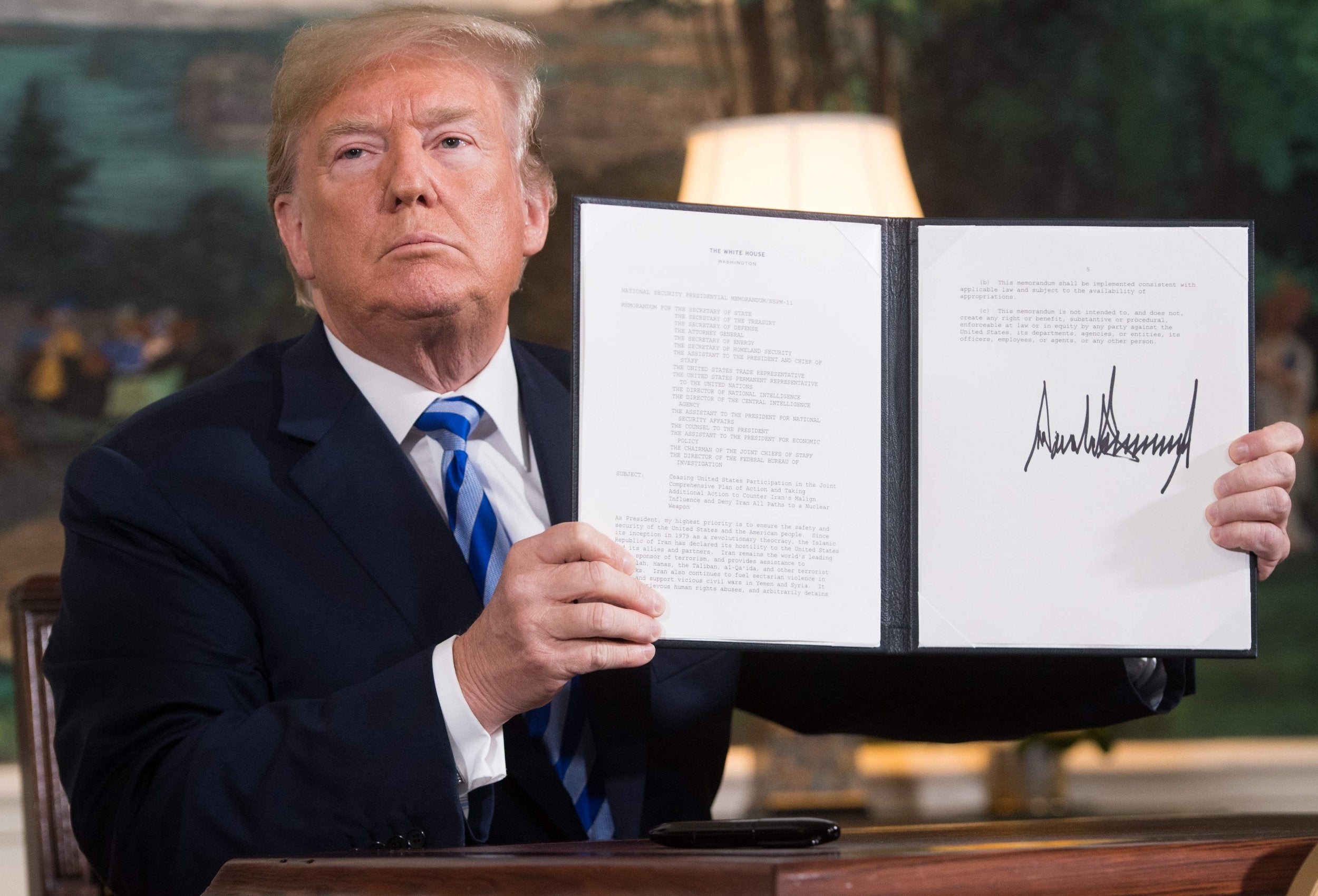 Donald Trump signs a document reinstating sanctions against Iran after announcing withdrawal from the nuclear deal in May 2018