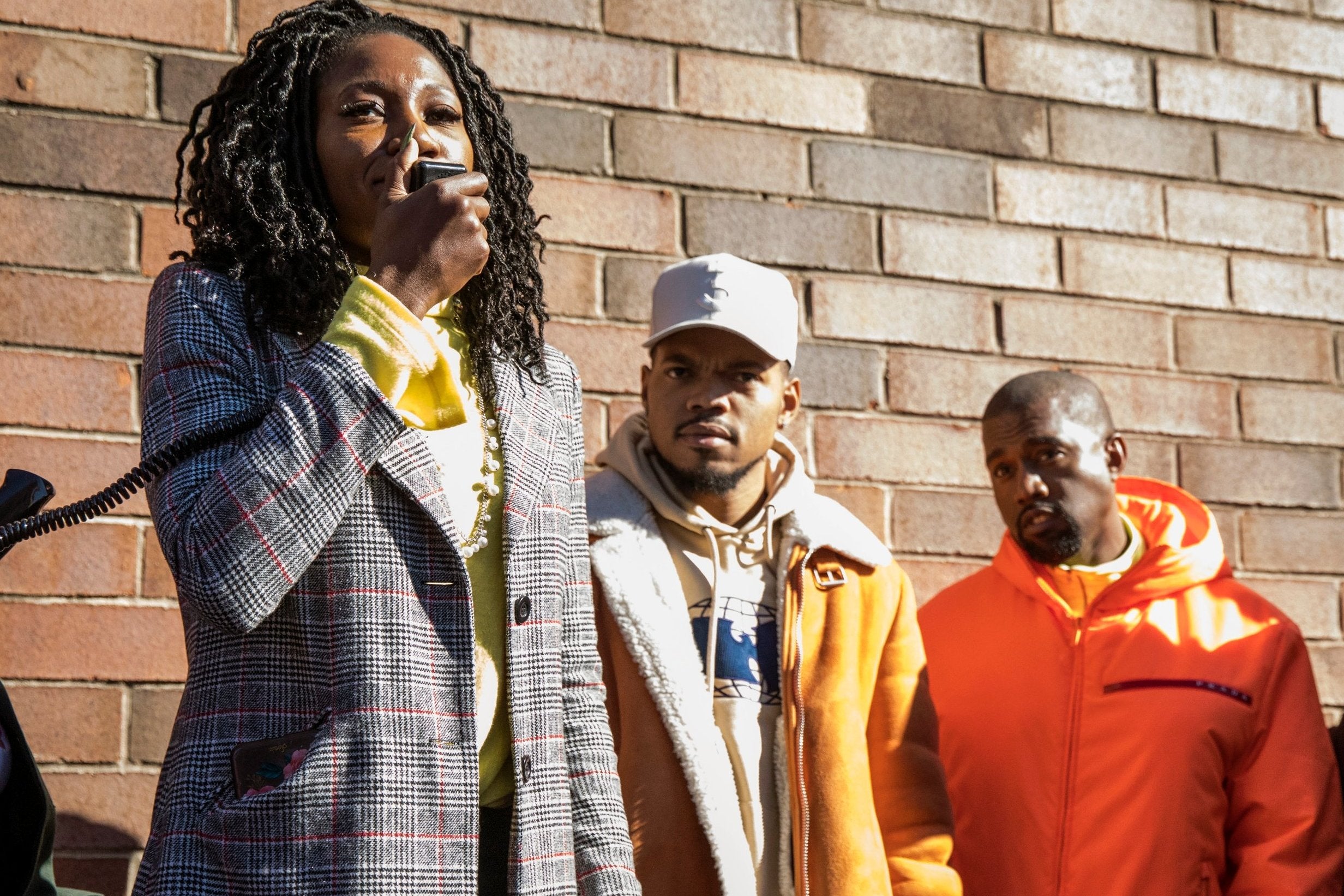 Chicago mayoral candidate Amara Enyia speaks as Chance the Rapper, center, and Kanye West listen during a "pull-up" rally for Enyia Tuesday, Oct. 23, 2018, in Chicago